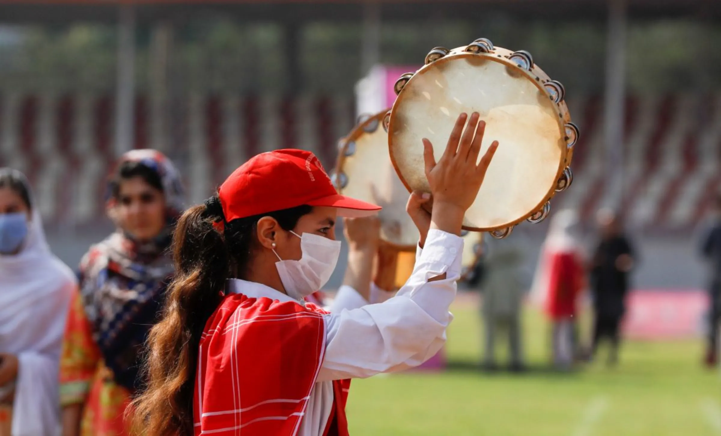 A girl wears a protective mask as she plays a tambourine with others during a sports event in connection with the International Women's Day celebrations in Peshawar, Pakistan March 8, 2021. REUTERS/Fayaz Aziz