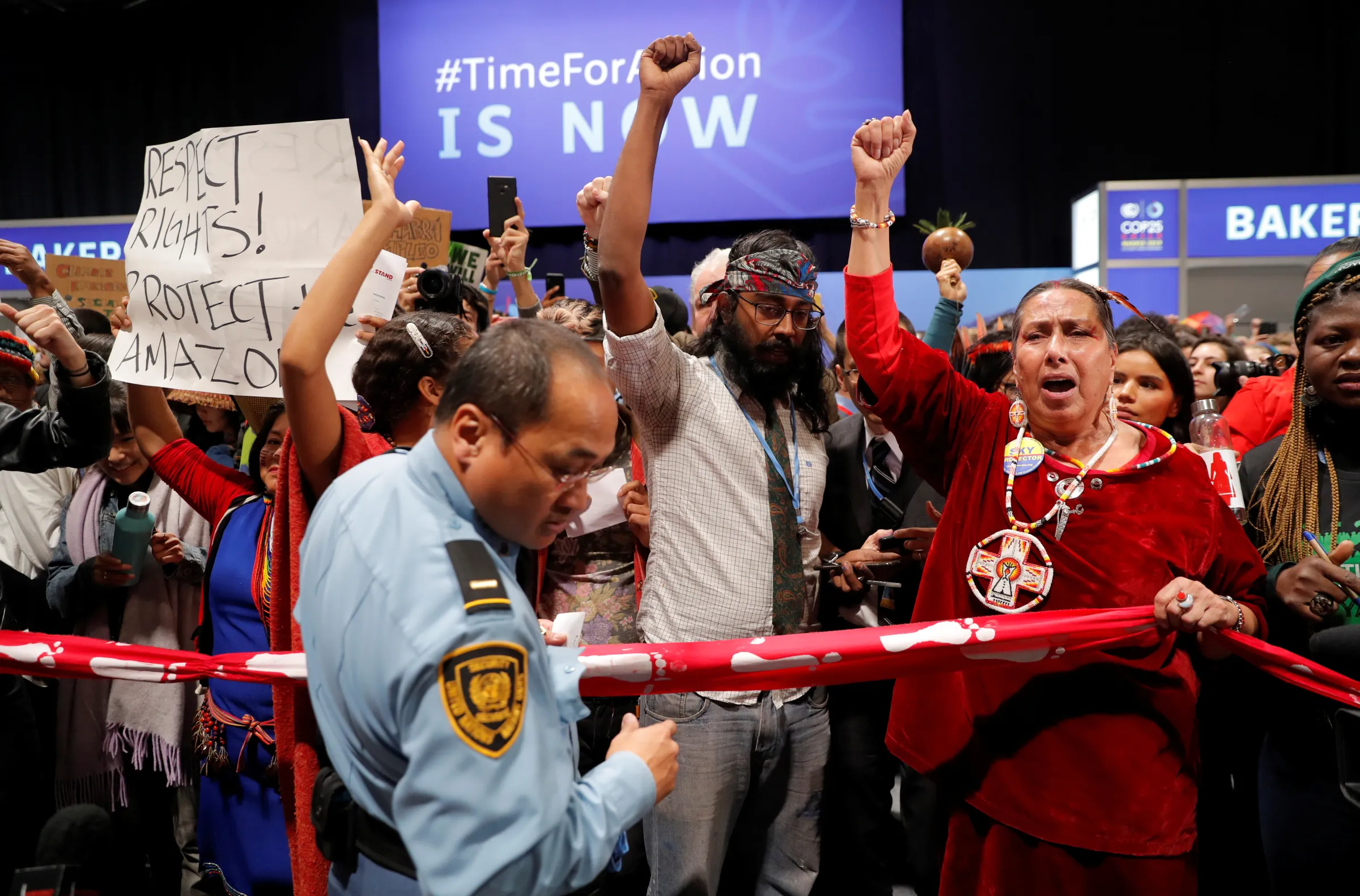 A security officer stands in front of climate activists gesturing outside the plenary room baker during the U.N. Climate Change Conference (COP25) in Madrid, Spain December 11, 2019. REUTERS/Susana Vera