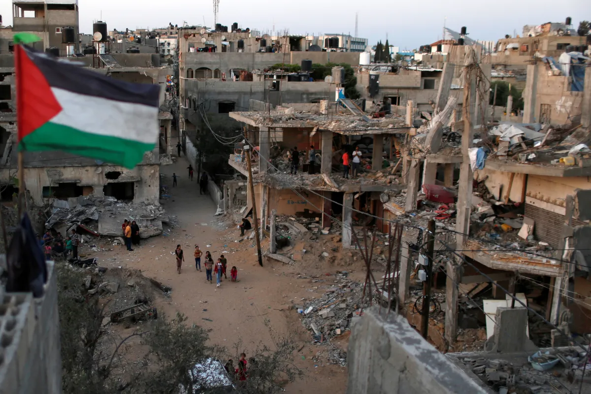 A Palestinian flag flies as the ruins of houses, which were destroyed by Israeli air strikes during the Israeli-Palestinian fighting