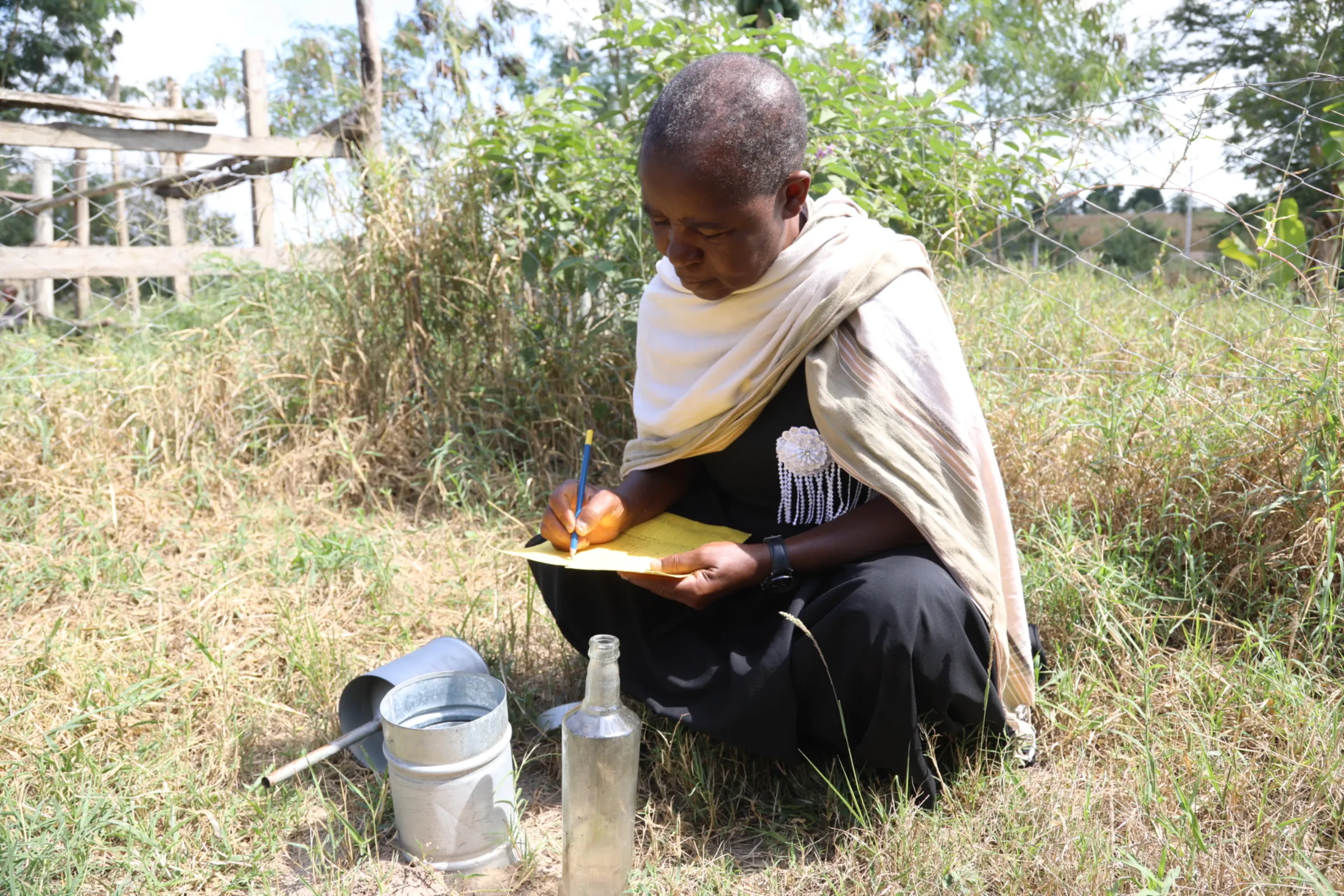 Teresa Kahindi, a 53-year-old farmer in Kilifi County, Kenya, recording daily rainfall at her farm to verify county data, August 5, 2024. Thomson Reuters Foundation/Peter Yeung