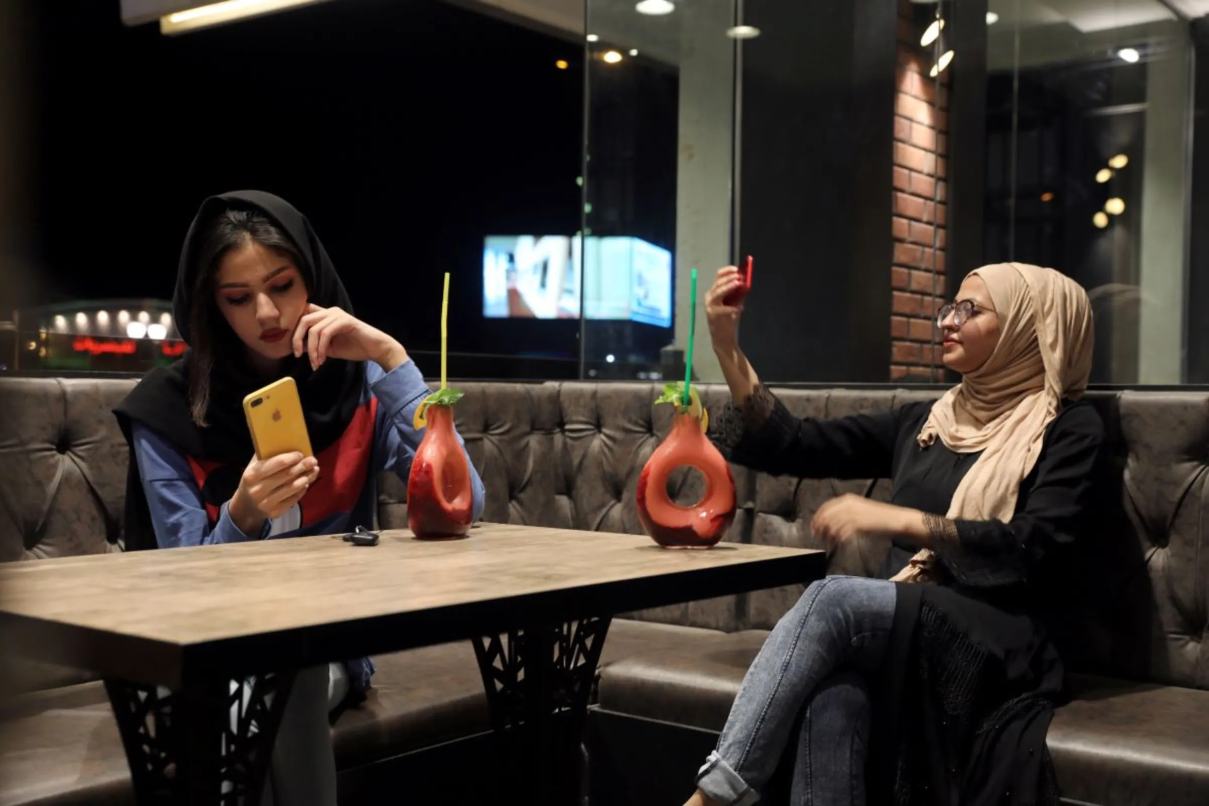 Iraqi girls use their phones at a cafe in Kerbala, Iraq August 6, 2019. Picture taken August 6, 2019. REUTERS/Abdullah Dhiaa Al-Deen