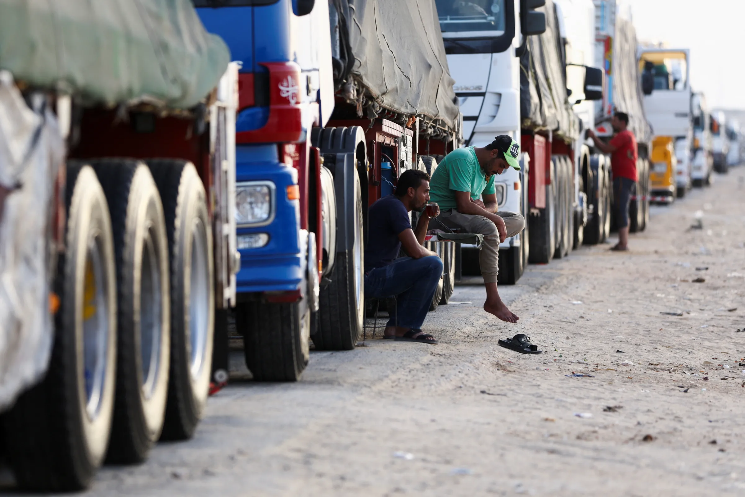 Truck drivers sit near lines of aid trucks for Gaza waiting to be deployed, in Al Arish, Egypt, July 4, 2024. REUTERS/Amr Alfiky