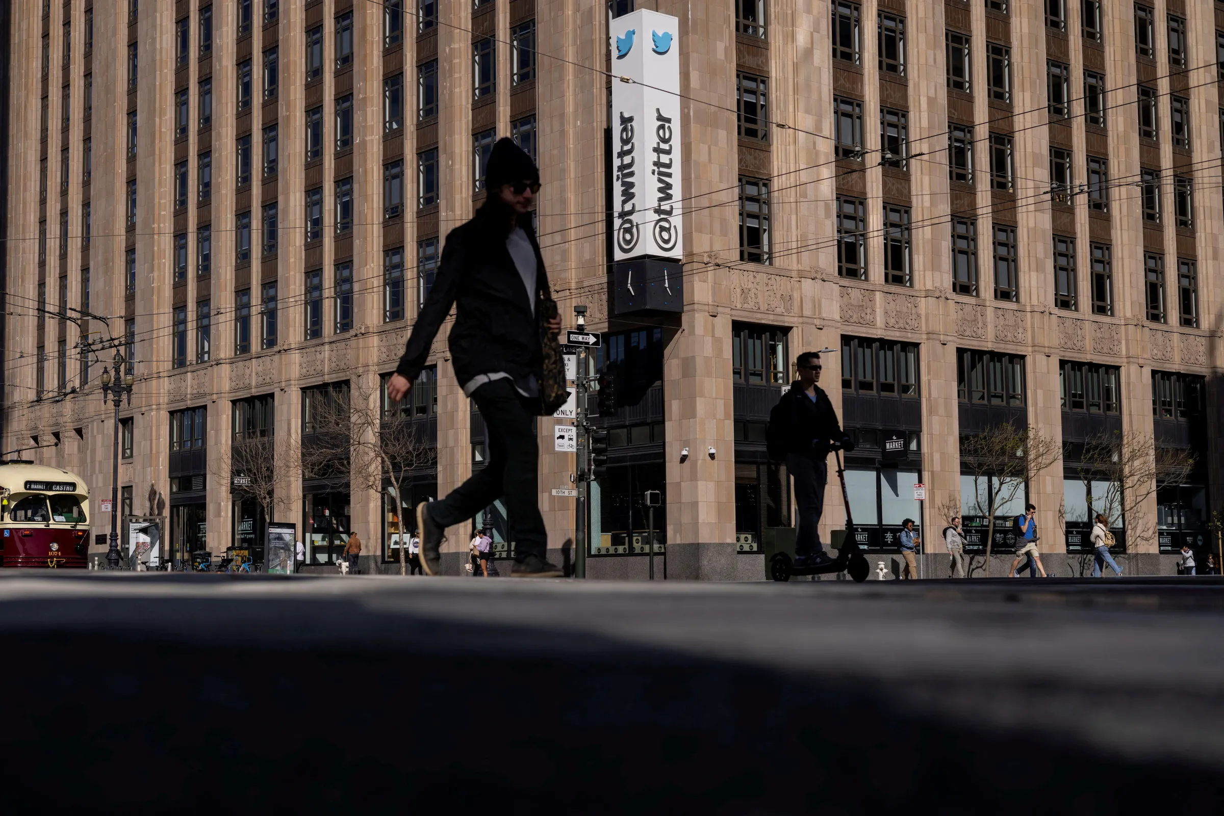 People walk by a Twitter logo at the company headquarters in downtown San Francisco, California, U.S., April 25, 2022