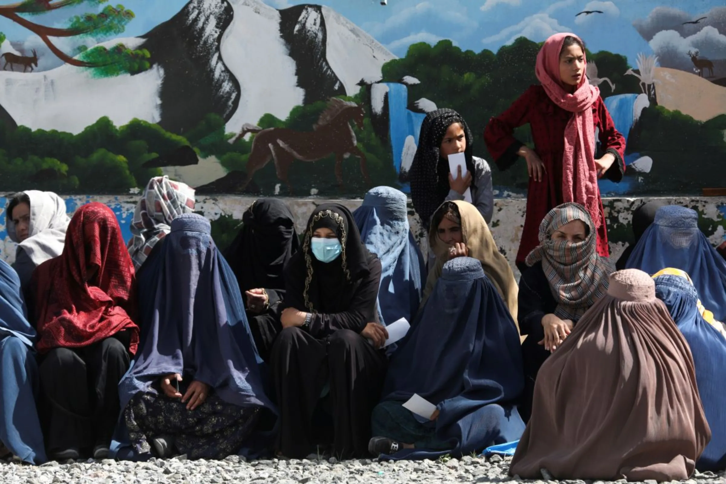 Afghan women wait to receive a food package being distributed by a humanitarian aid group at a distribution center in Kabul, Afghanistan, April 25, 2022