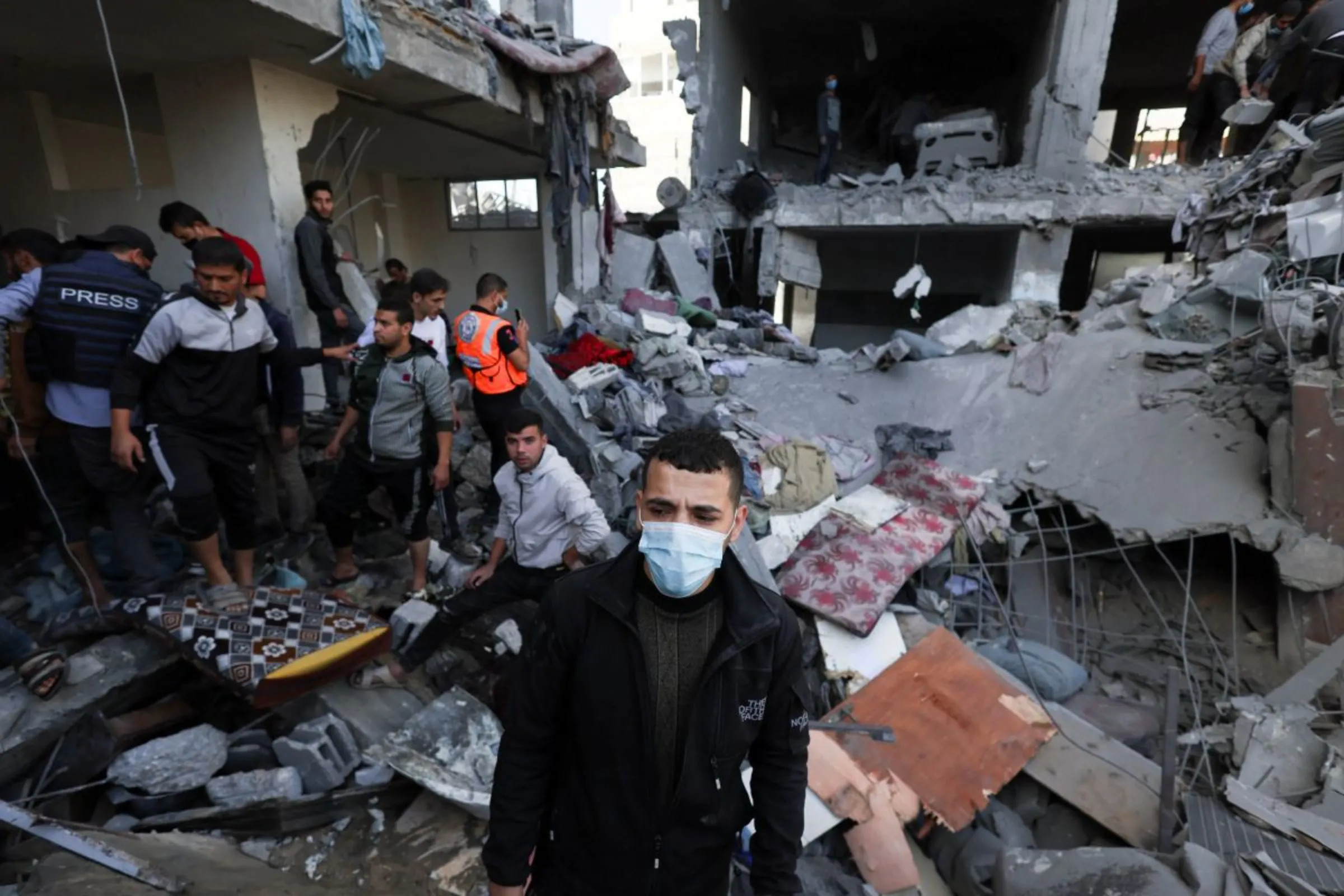 A Palestinian man wears a protective face mask as others search for casualties at the site of an Israeli strike on a house in Rafah, amid the ongoing conflict between Israel and the Palestinian Islamist group Hamas, in the southern Gaza Strip November 23, 2023. REUTERS/Ibraheem Abu Mustafa