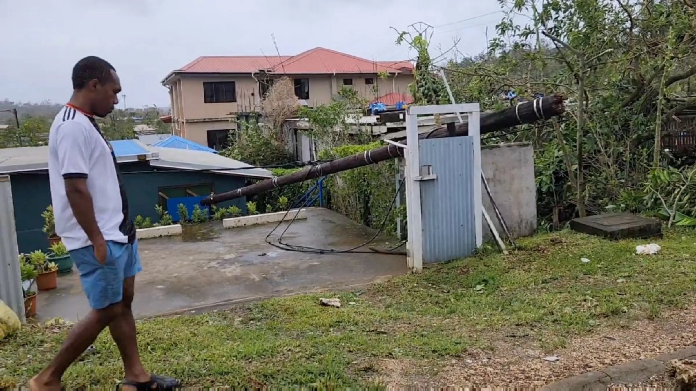 A man walks next to a fallen pole in the aftermath of cyclone Kevin, in Port Vila, Vanuatu March 4, 2023, in this screen grab obtained from a social media video. DevMode/via REUTERS