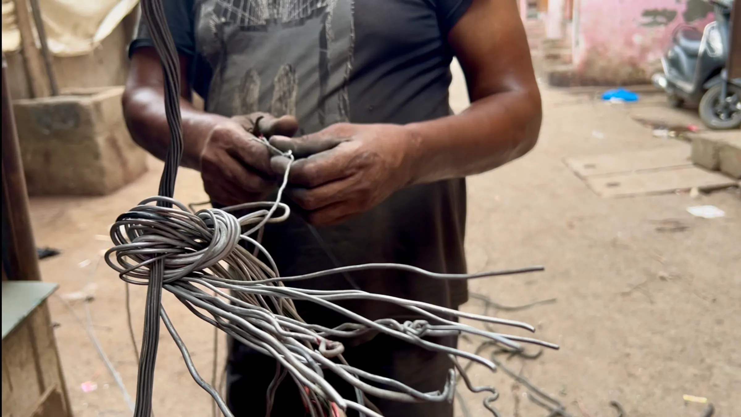 Mohammed Saleem, an informal e-waste recycling worker, peels old wires to extract aluminium and copper in Seelampur, Delhi. July 12, 2025. Thomson Reuters Foundation/Bhasker Tripathi