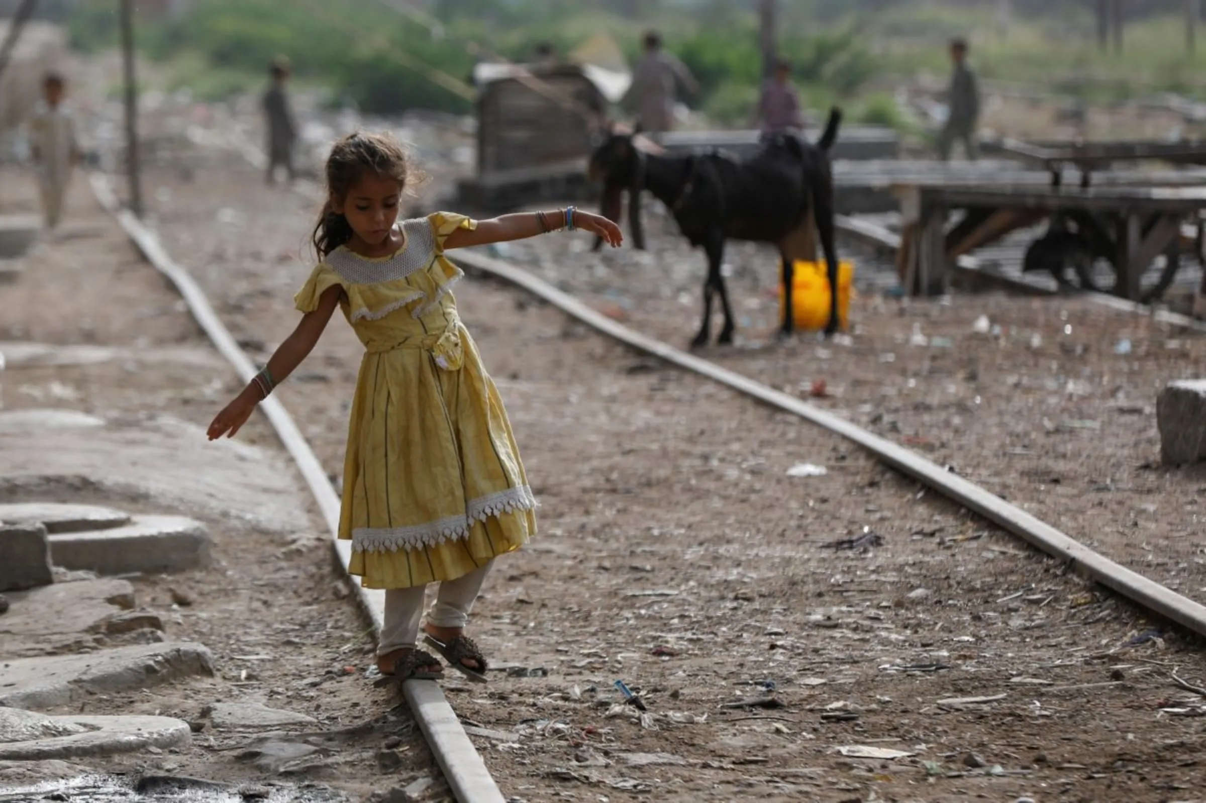 A girl balances herself while walking on an abandoned railway track in a slum area in Karachi, Pakistan July 10, 2023. REUTERS/Akhtar Soomro