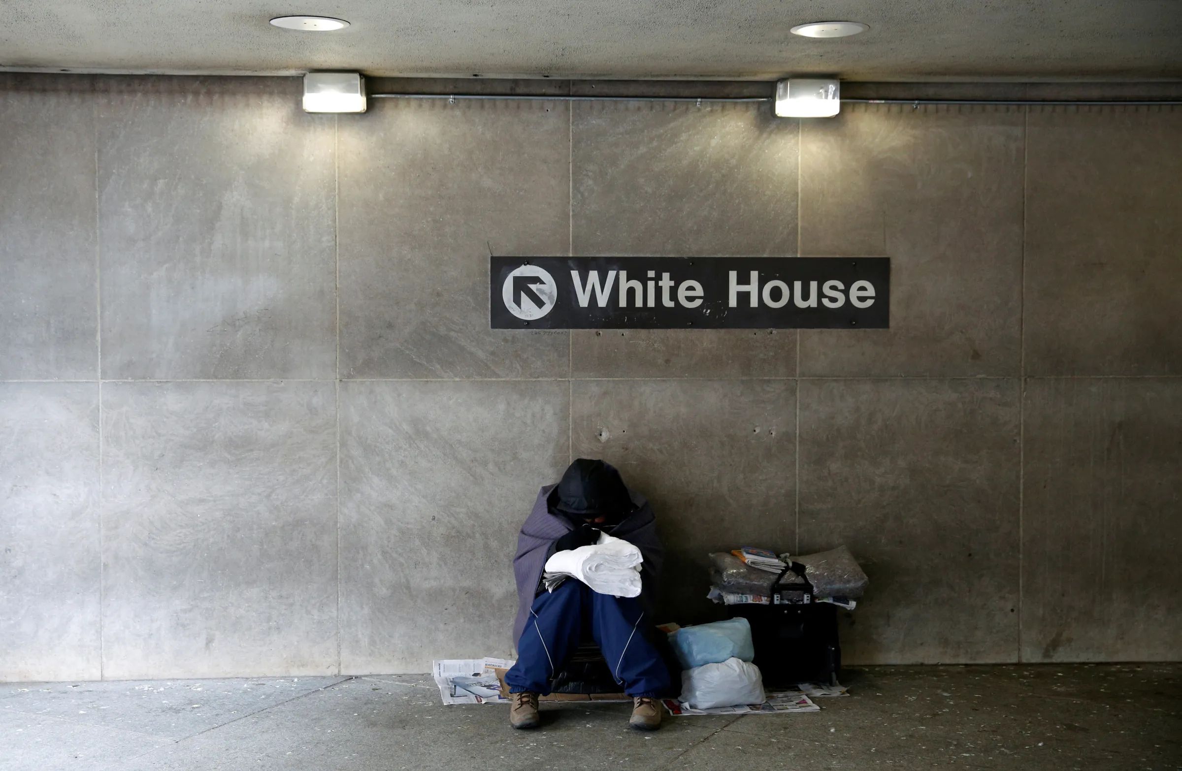 On an unseasonably cold day, a homeless person tries to stay warm at the entrance of a subway station near the White House in Washington January 20, 2016