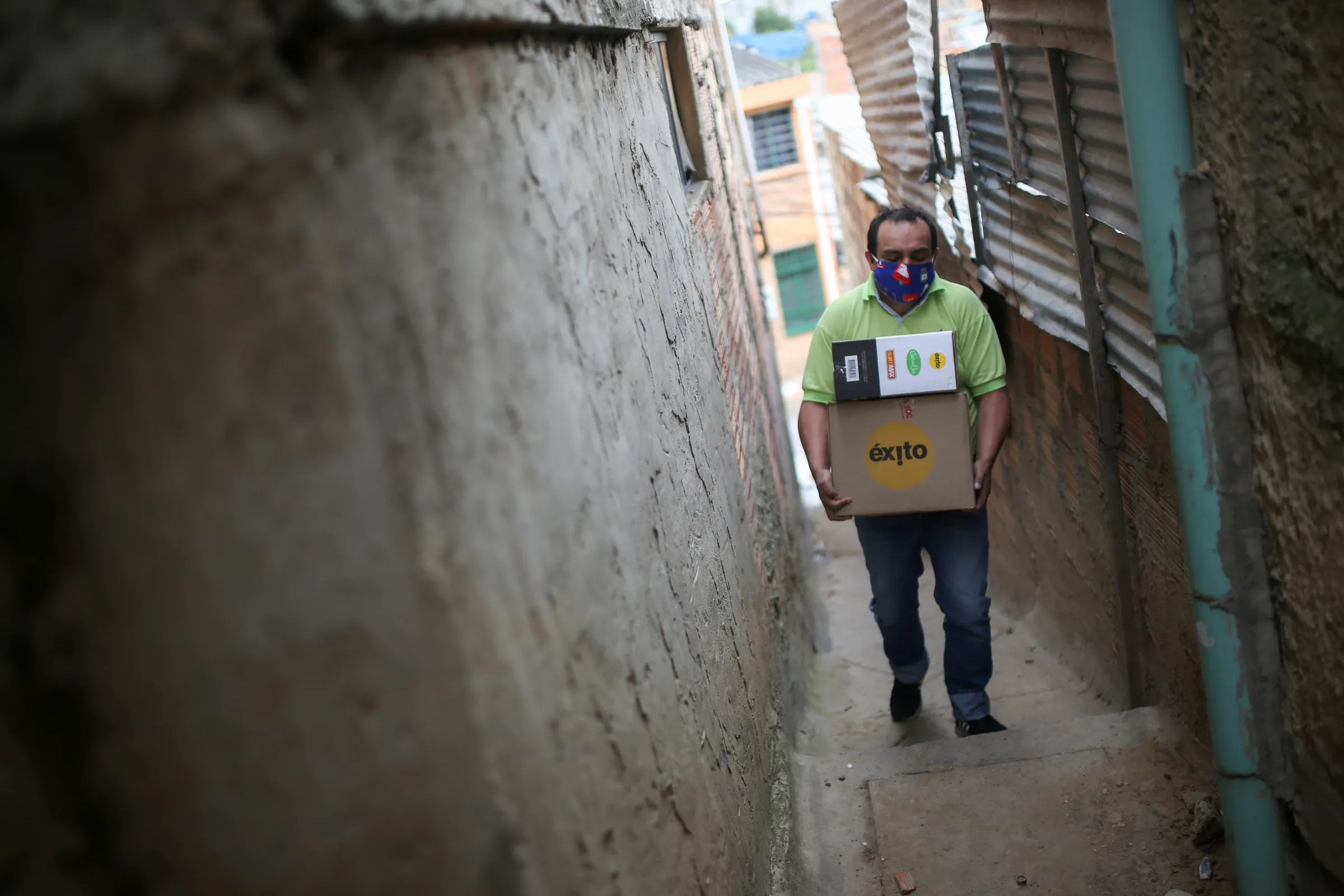 A man carrying boxes walks down a narrow road