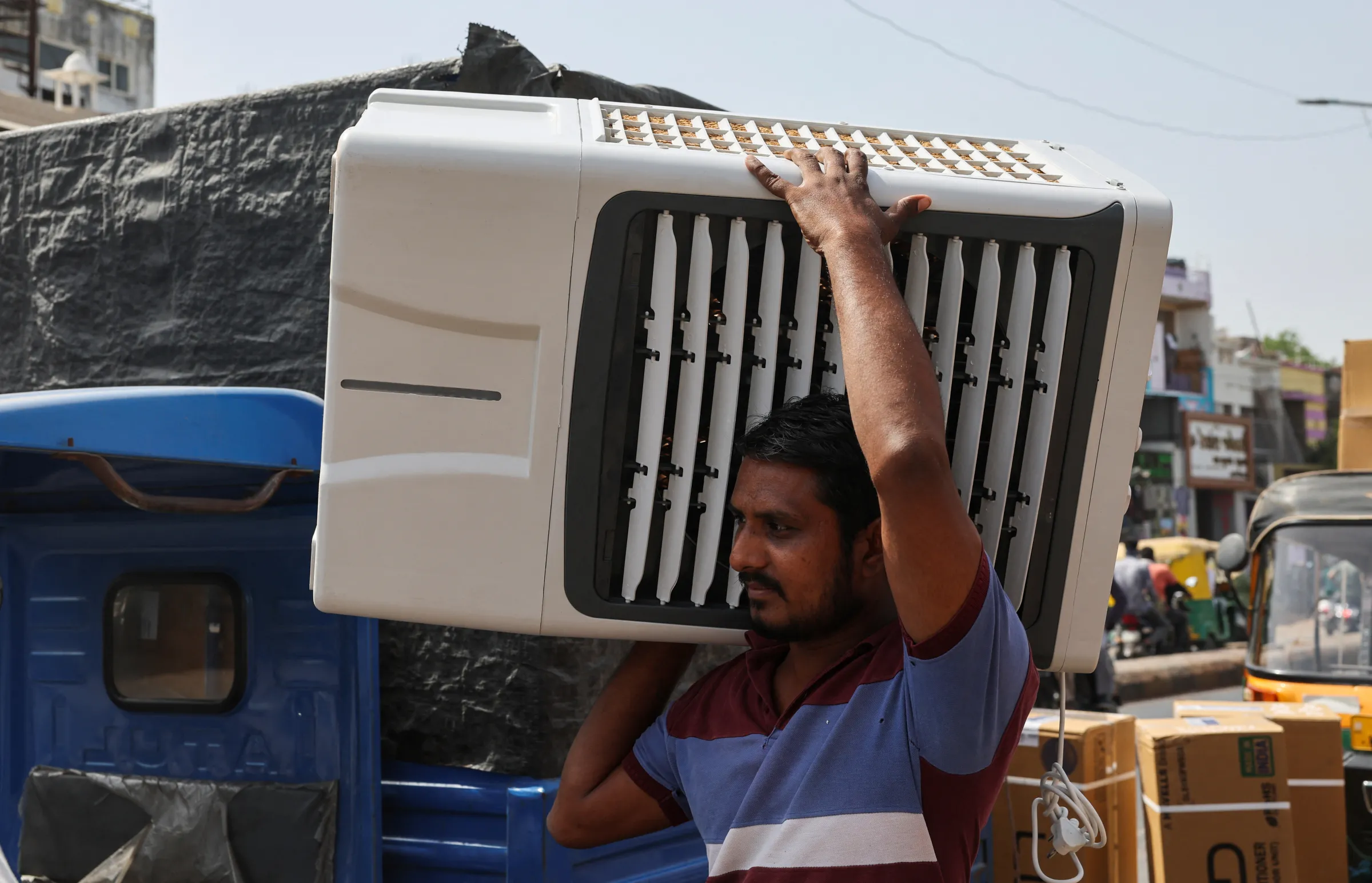 A worker carries an air cooler for delivery to a customer during the heat wave in Ahmedabad, India, May 30, 2024. REUTERS/Amit Dave