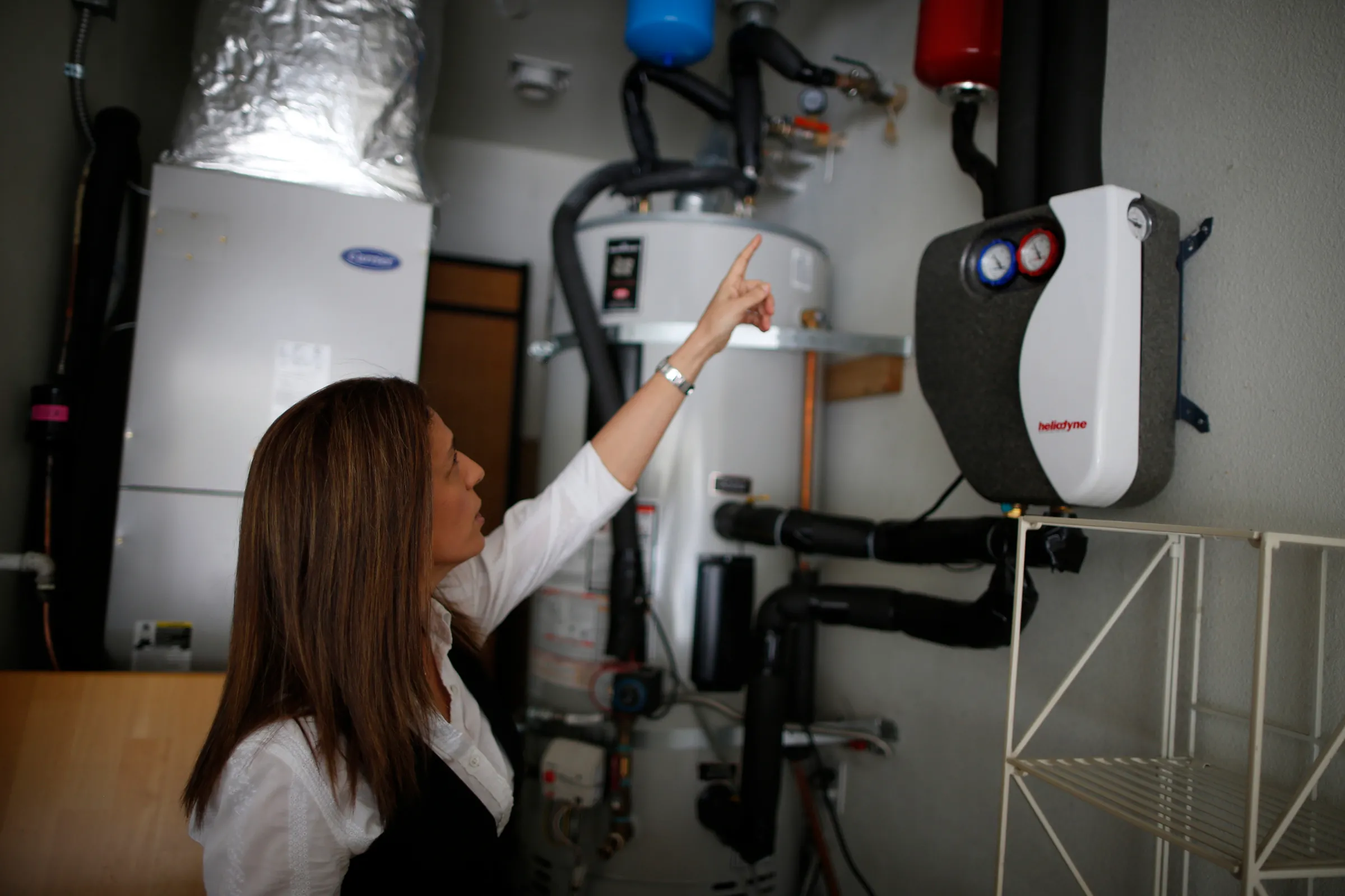 A woman points to a domestic hot water solar system in her home in Irvine, California January 26, 2015. EDISON-LABS/ REUTERS/Lucy Nicholson