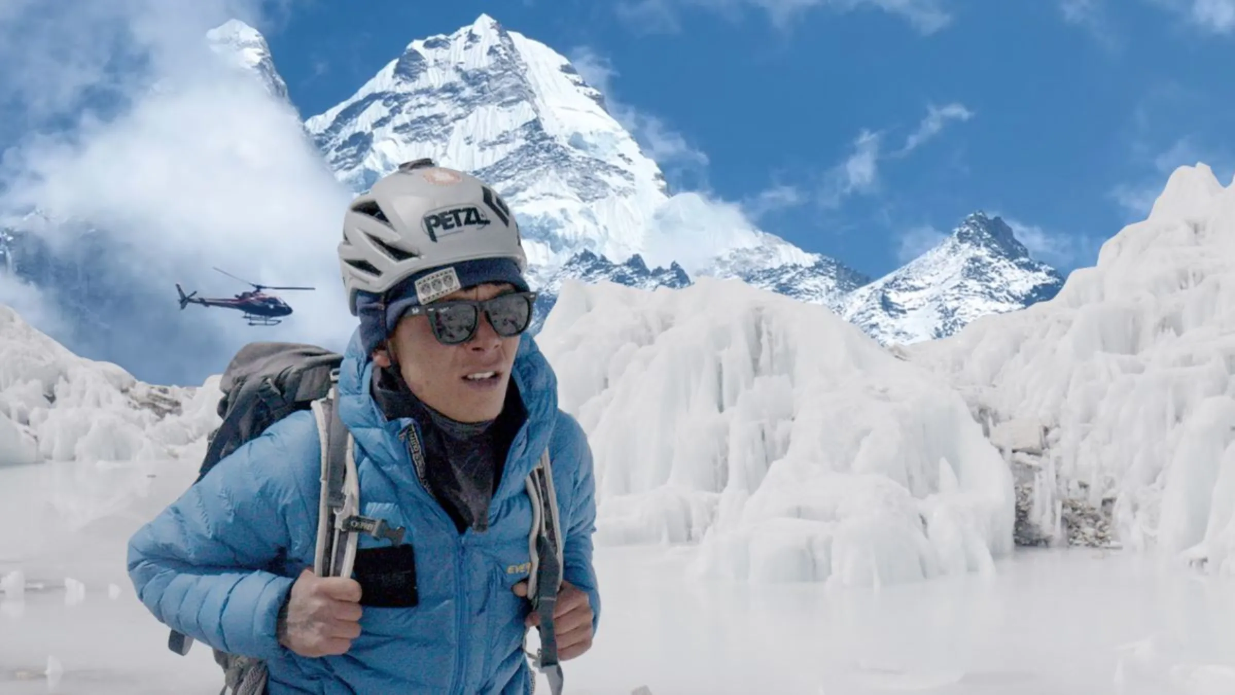 An icefall doctor, whose job is to make the climbing routes as safest as possible, stands in front of the the Khumbu Icefalls glaciers on the Mount Everest as a helicopter flies in the background, in this video still