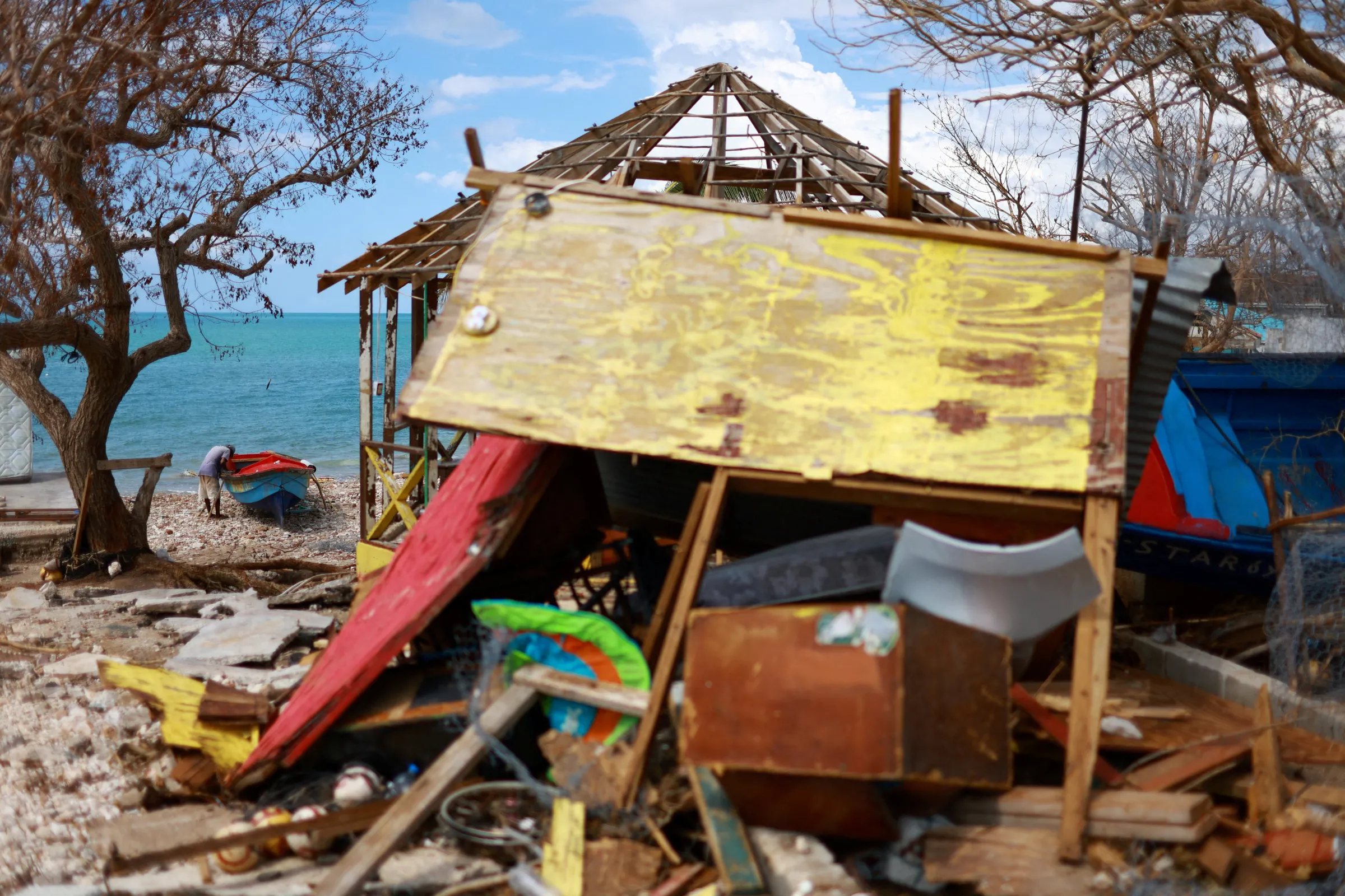 A fisherman fixes his boat, damaged by Hurricane Melissa, on Treasure Beach, in St. Elizabeth, Jamaica, November 5, 2025. REUTERS/Raquel Cunha