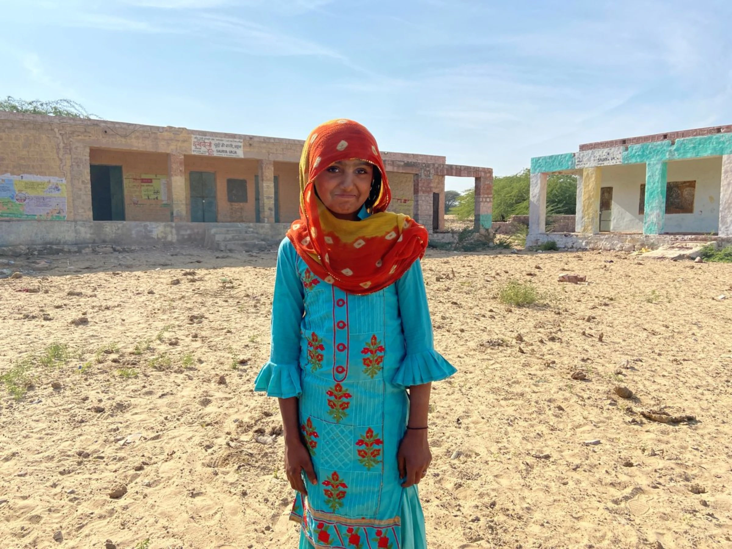 A child poses in front of the village school that shut down two years ago in Bhadla, Rajasthan, India, December 11, 2021