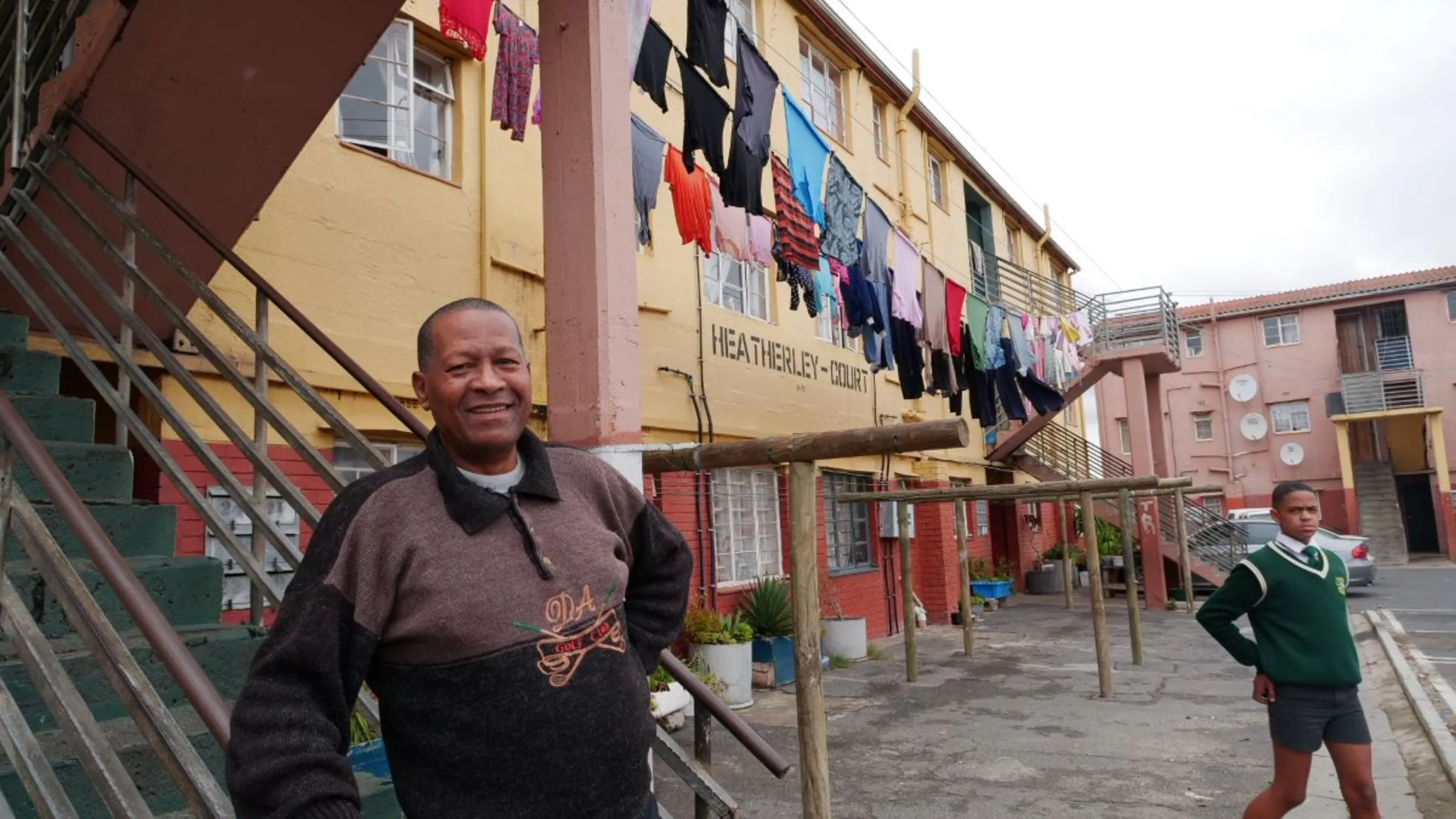 Music teacher and former police detective Tommy Jooste who now teaches gangsters musical instruments smiles for a photo by the stairs of his apartment in the Scottsdene neighbourhood in Cape Town, South Africa, March 9, 2023. Thomson Reuters Foundation/Kim Harrisberg