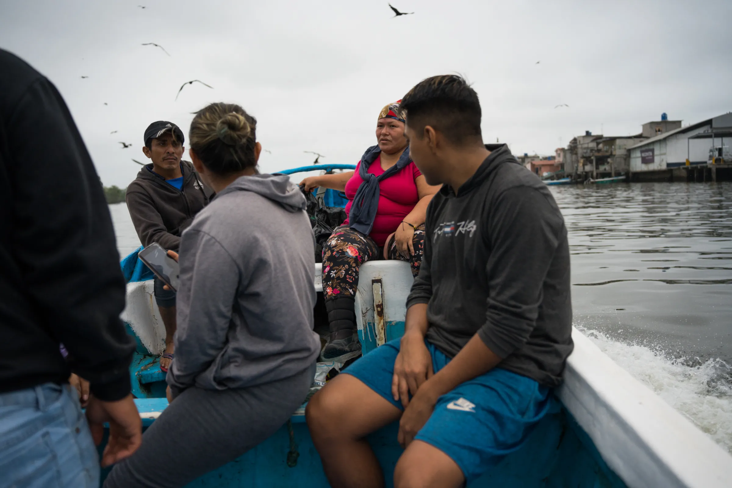 A man sits with his back turned to the camera in a boat full of people