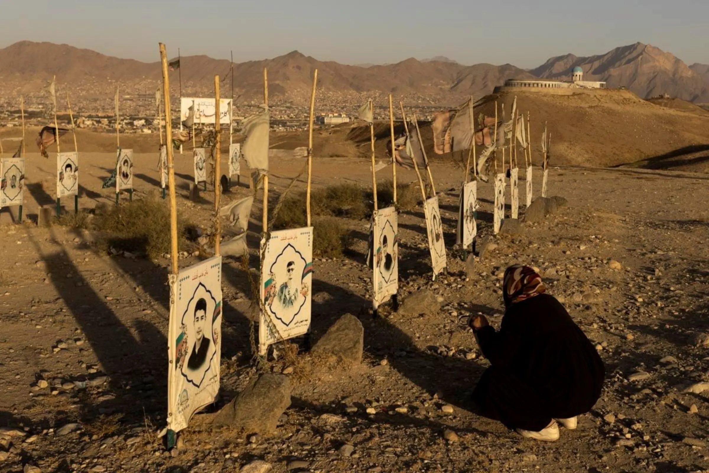 A woman prays in front of the graves at a Hazara cemetery for the Shi'ite community martyrs on a hill on the outskirts of Kabul, Afghanistan October 20, 2021.  REUTERS/Jorge Silva