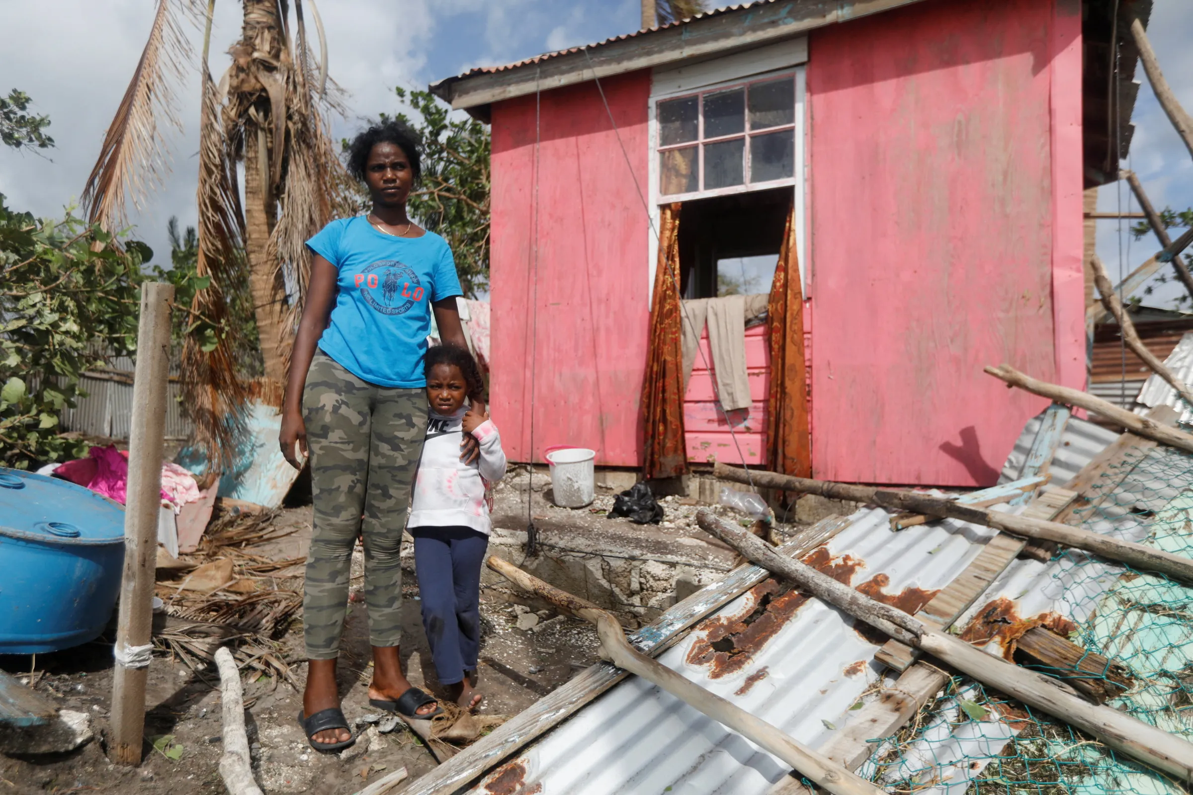 A mother and child stand outside of their home after Hurricane Melissa made landfall, in Alligator Pond, Jamaica, October 29, 2025. REUTERS/Octavio Jones