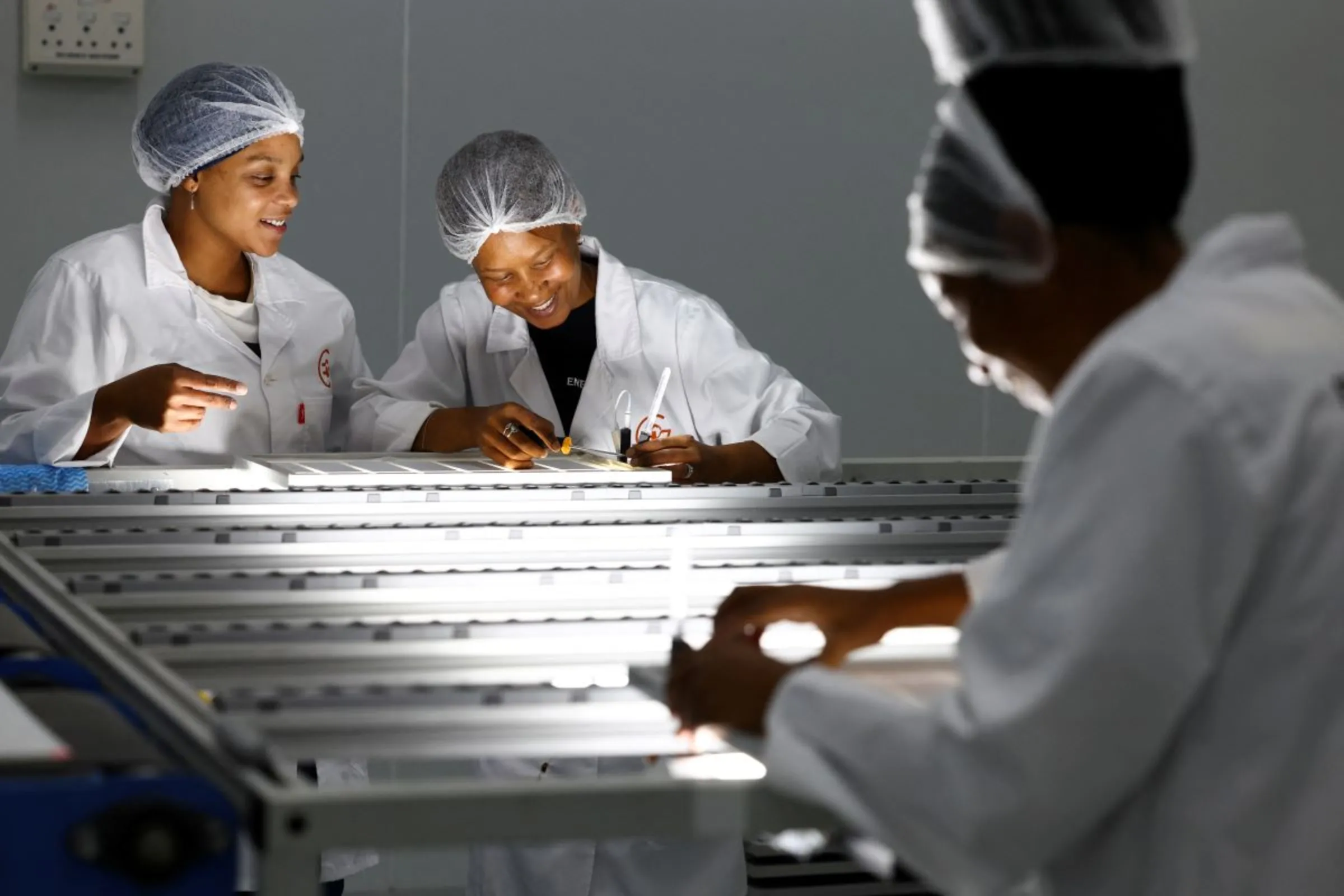 Women interact, as they test LED lights on solar panels, at a factory called Ener-G-Africa, where they produce high-quality solar panels made by an all-women team, in Cape Town, South Africa, February 9, 2023