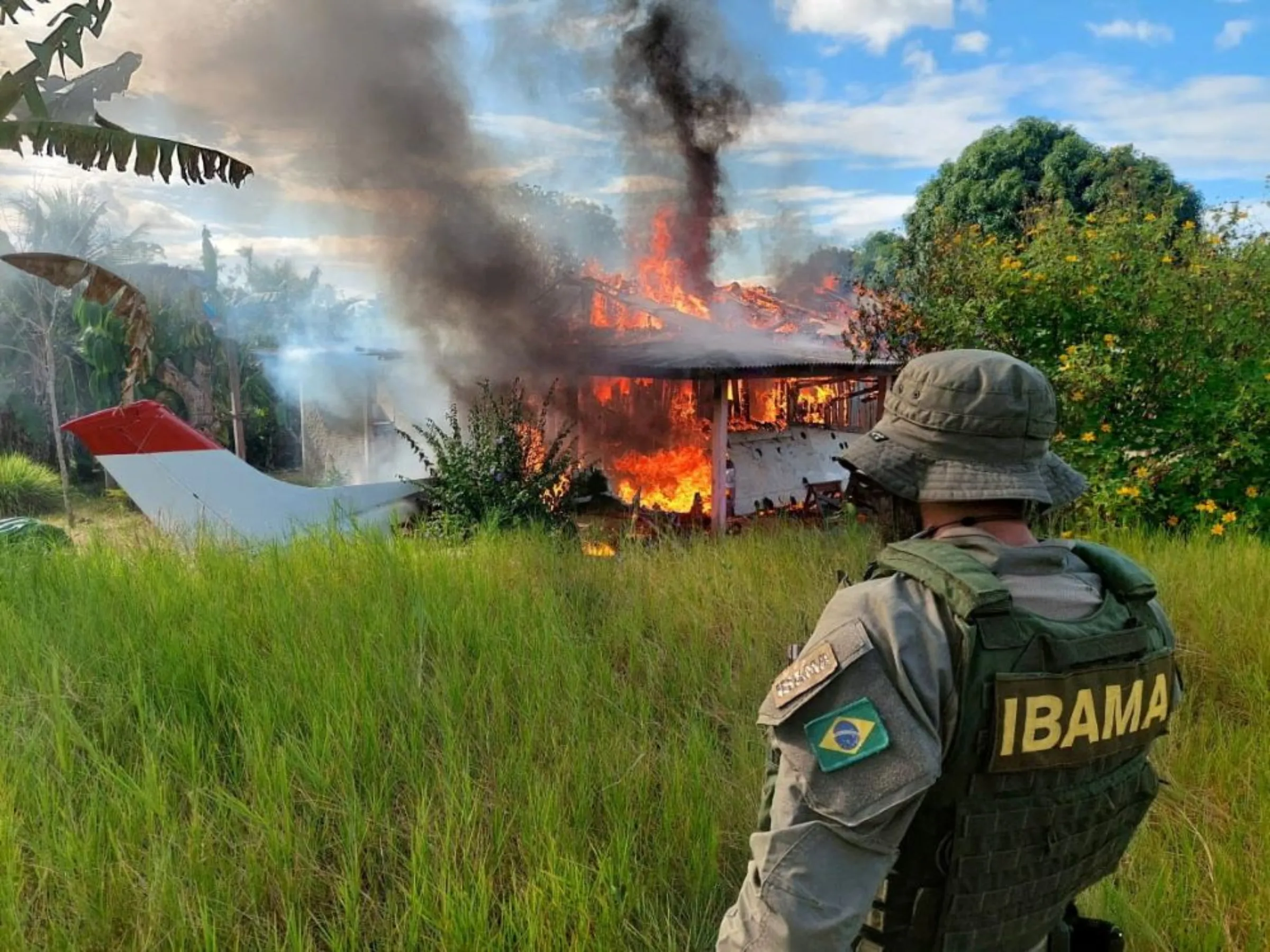 An agent of the Brazilian Institute for the Environment and Renewable Natural Resources (IBAMA), looks on as a plane and a house belonging to miners are destroyed during an operation conducted jointly within Brazil's National Indian Foundation (FUNAI) and Brazilian National Public Security Force against illegal mining in Yanomami indigenous land in Roraima state, Brazil February 6, 2023