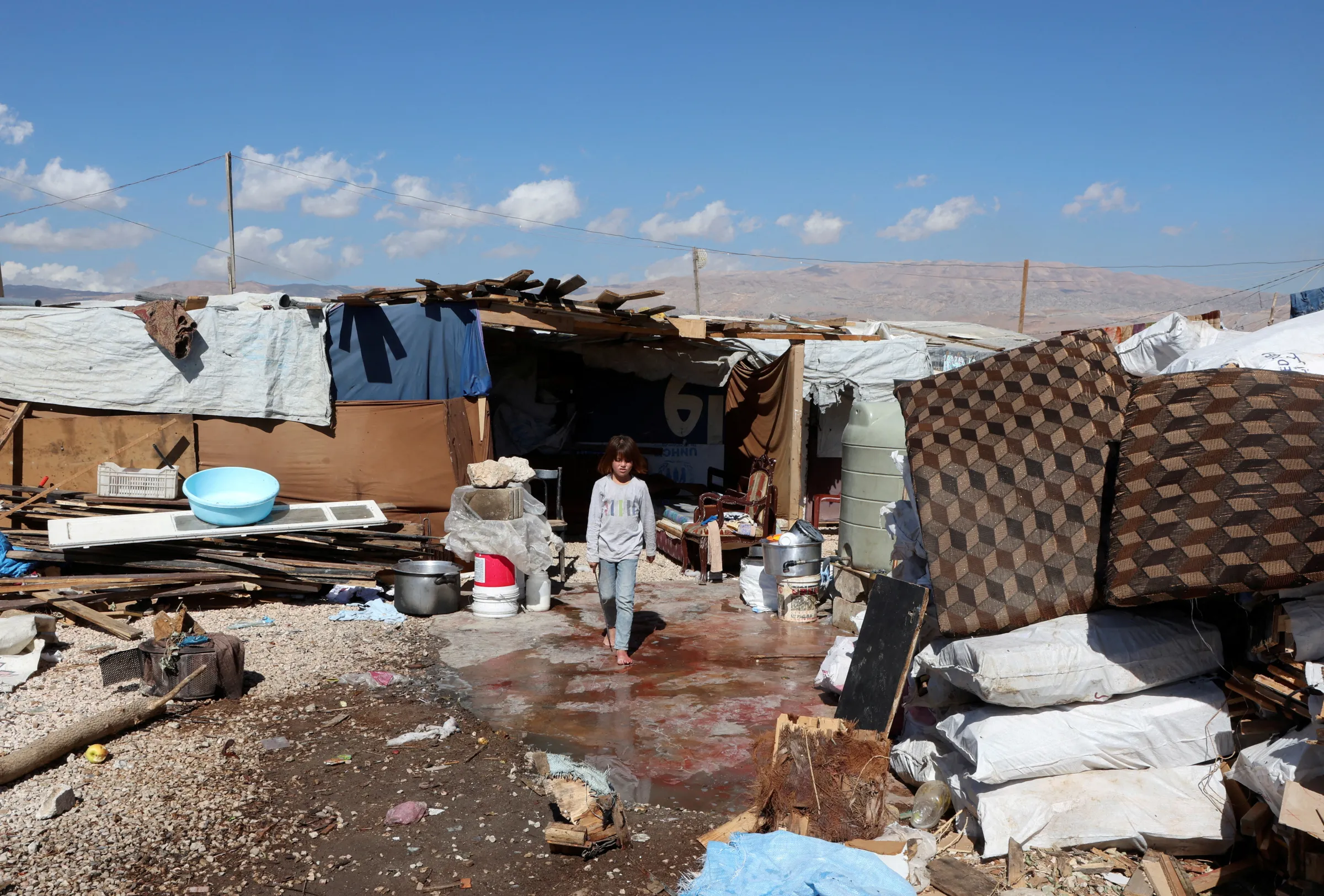 A girl walks outside tents at an informal camp for Syrian refugees in Qab Elias, in Lebanon's Bekaa Valley October 18, 2022