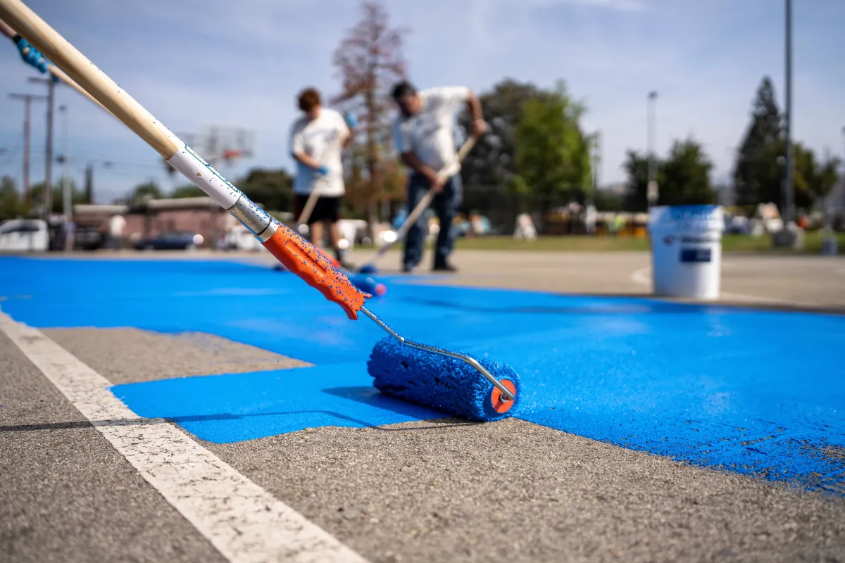 Volunteers paint a basketball court with a reflective treatment in the Los Angeles neighborhood of Pacoima in July 2022