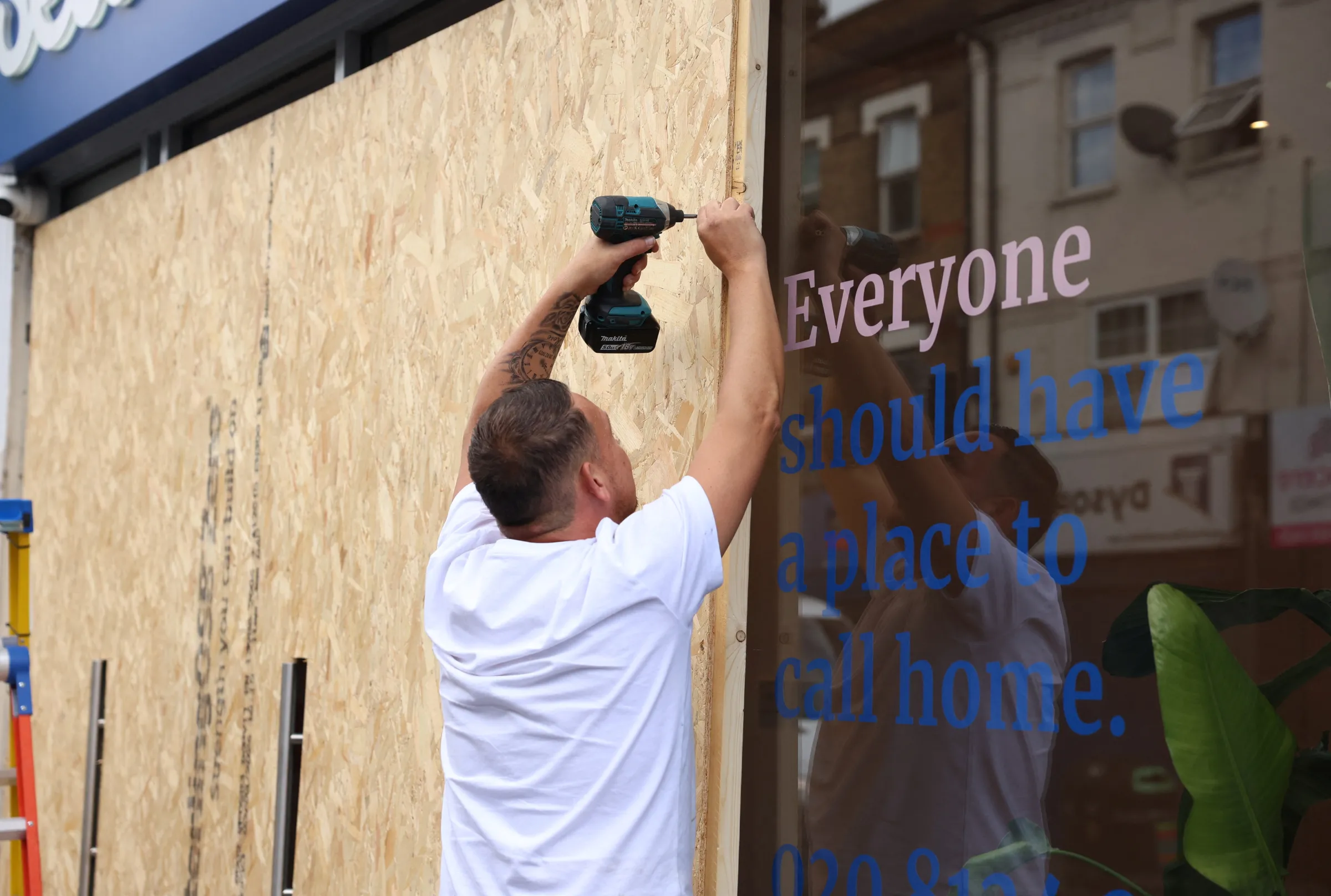 A person boards up windows as a protective measure against damage from riots, in preparation for more unrest amidst anti-immigration related rioting across the country, in London, Britain, August 7, 2024. REUTERS/Mina Kim