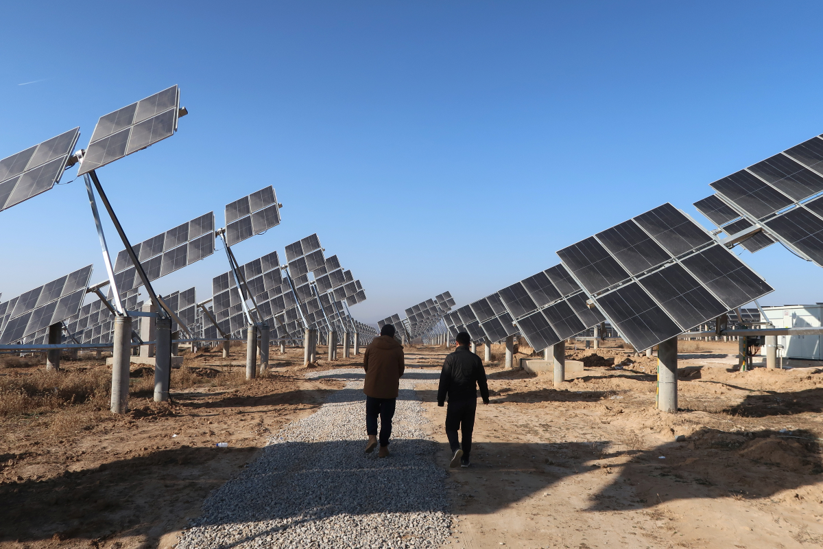Workers walk at a solar power station