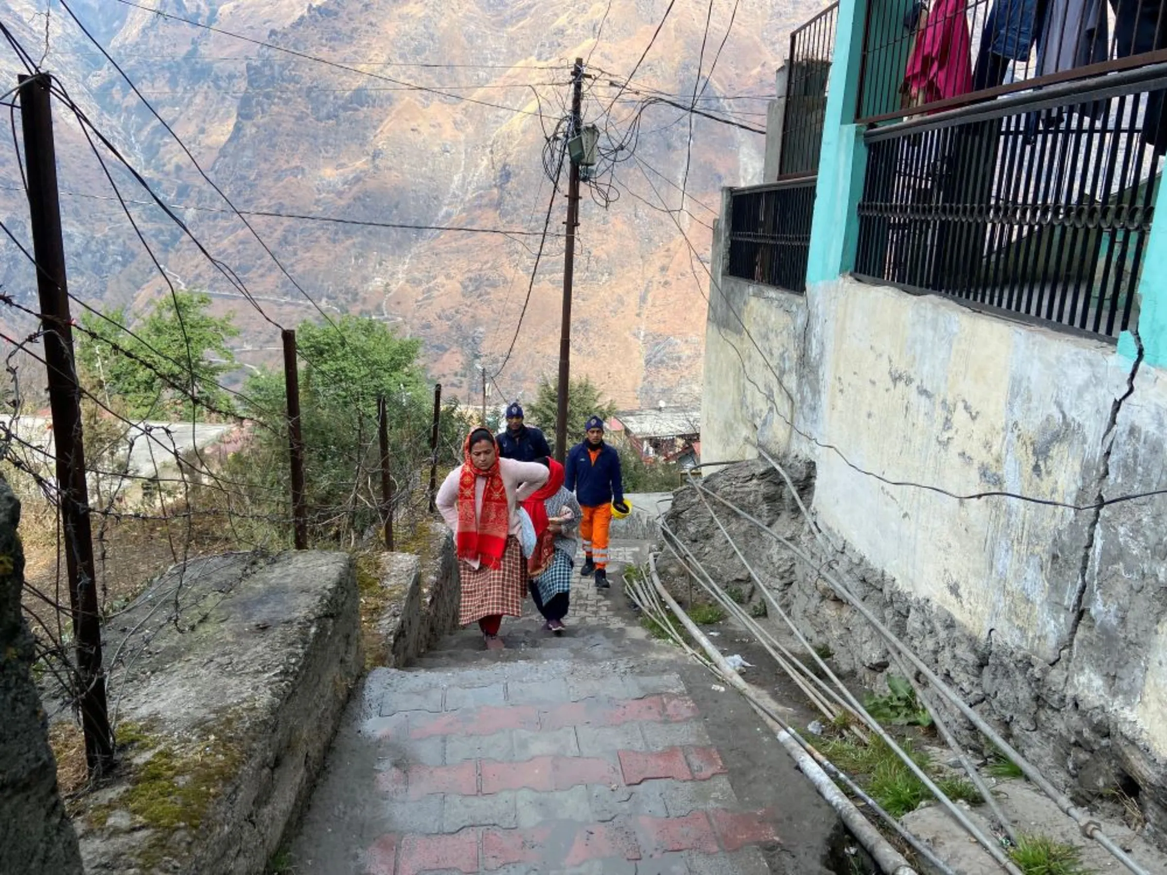 Personnel from disaster response brought in for evacuations from crumbling buildings walk on the steps of Joshimath, India, January 12, 2023