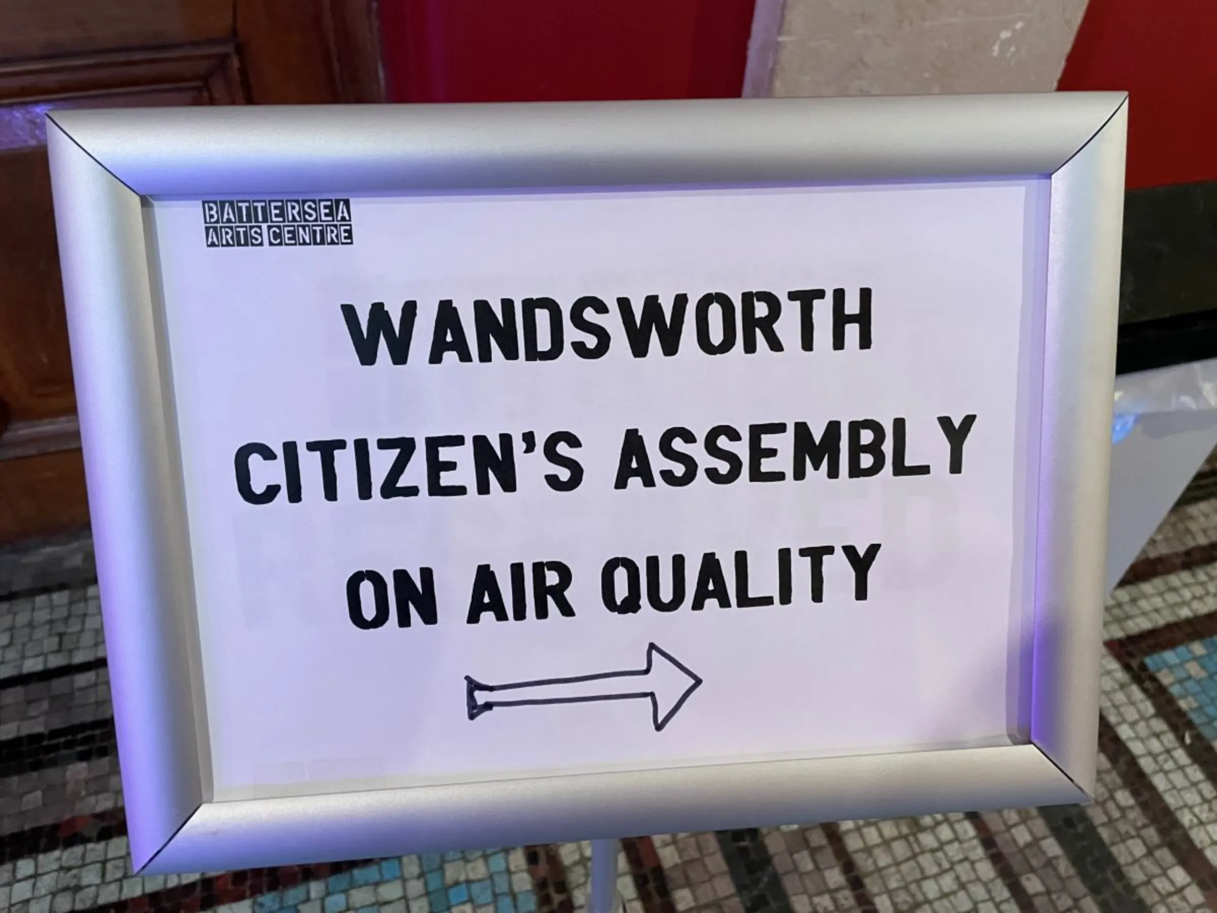 A welcome sign points participants to the first citizen’s assembly on air quality held in the London borough of Wandsworth, February 25, 2023. Thomson Reuters Foundation/Laurie Goering