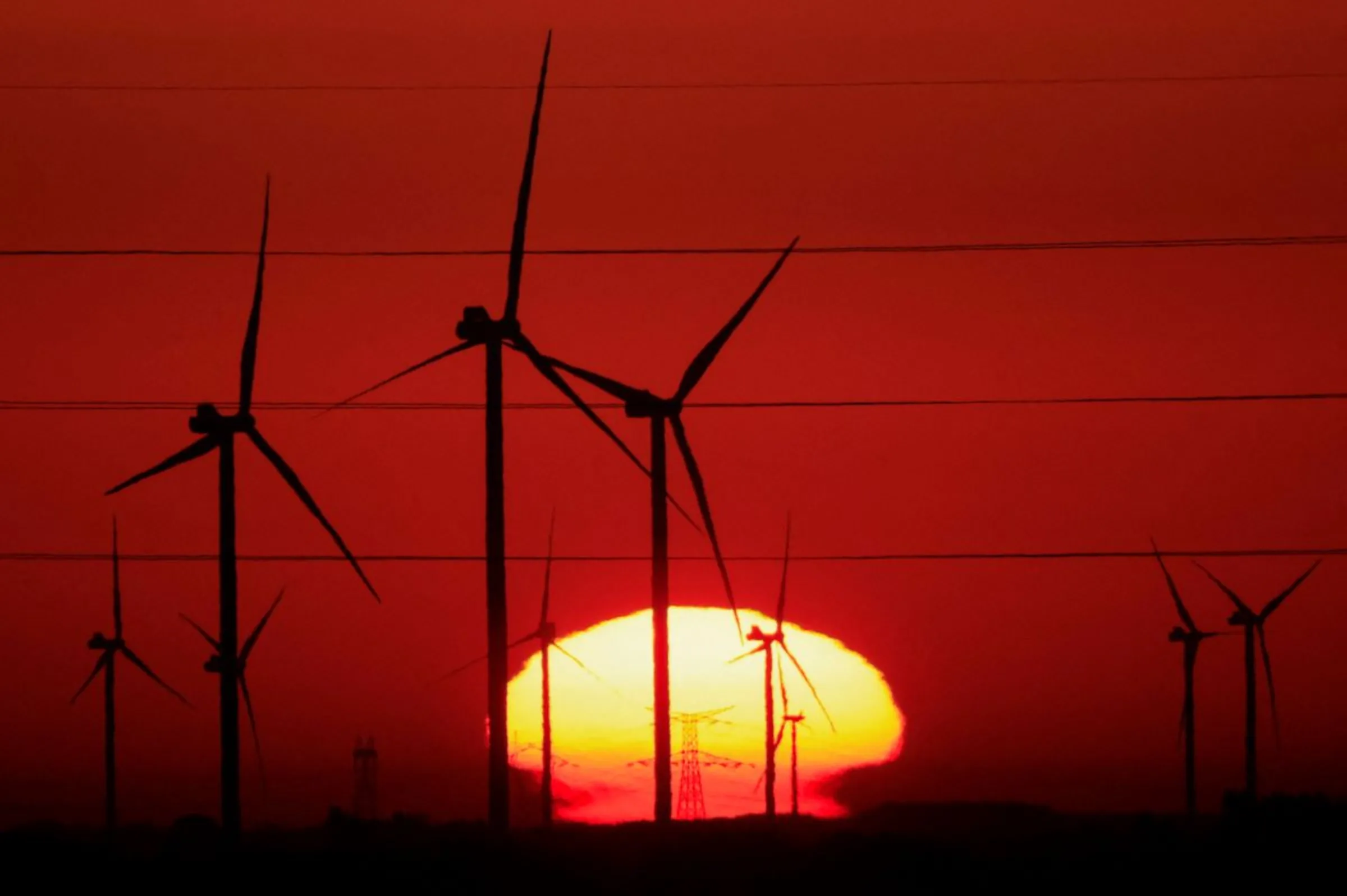 Power-generating windmill turbines and electricity pylons are pictured during sunrise at a wind park in Avesnes-le-Sec, France, September 8, 2023