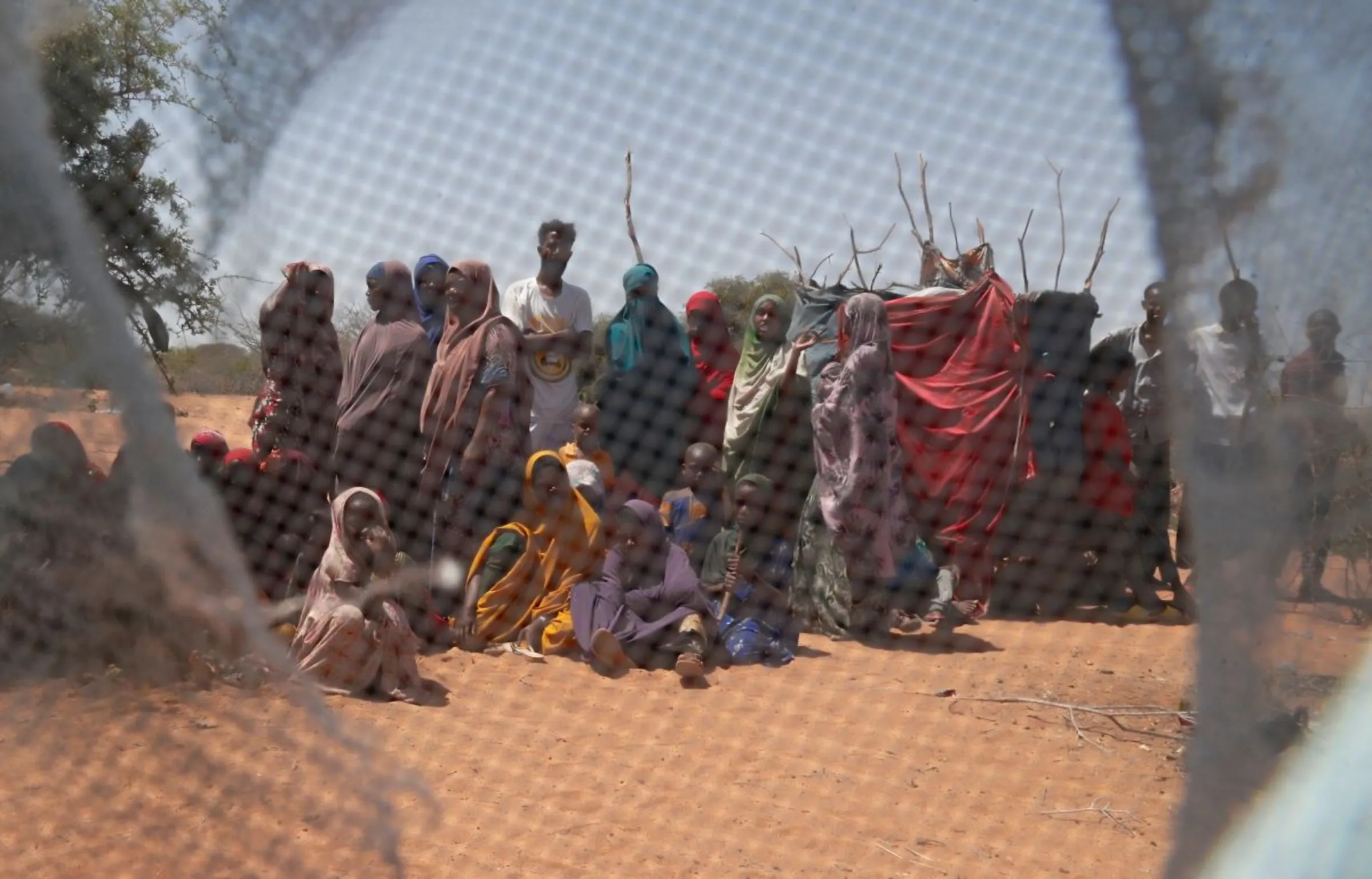 Somali refugees are seen through a discarded mosquito net as they gather in the new arrivals area of the Hagadera refugee camp in Dadaab, near the Kenya-Somalia border, in Garissa County, Kenya, January 17, 2023. REUTERS/Thomas Mukoya