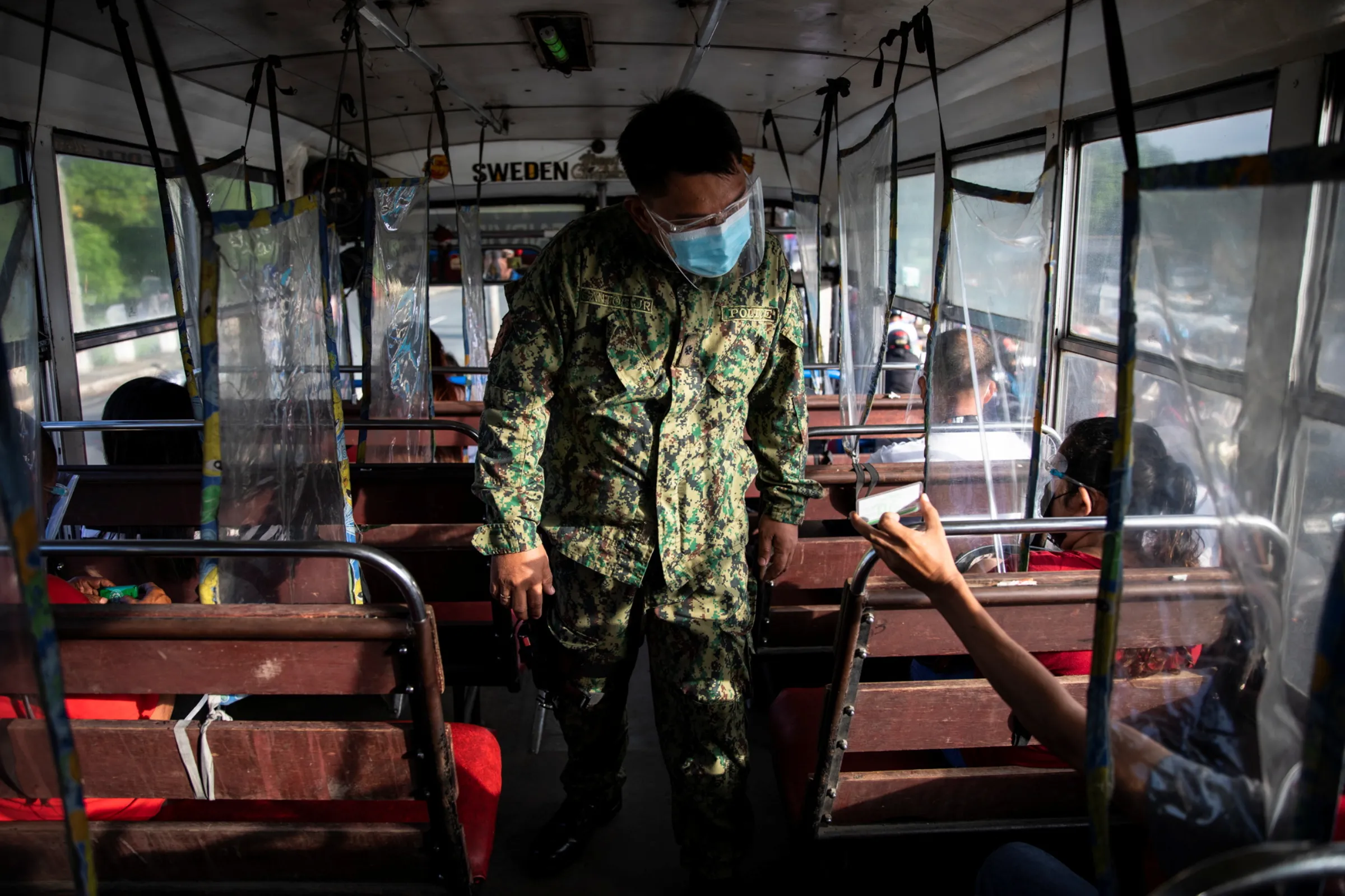 A policeman inspects an ID of a bus passenger passing through a checkpoint on the first day of a two-week lockdown to prevent the spread of the highly infectious coronavirus Delta variant, in Quezon City, Metro Manila, Philippines, August 6, 2021