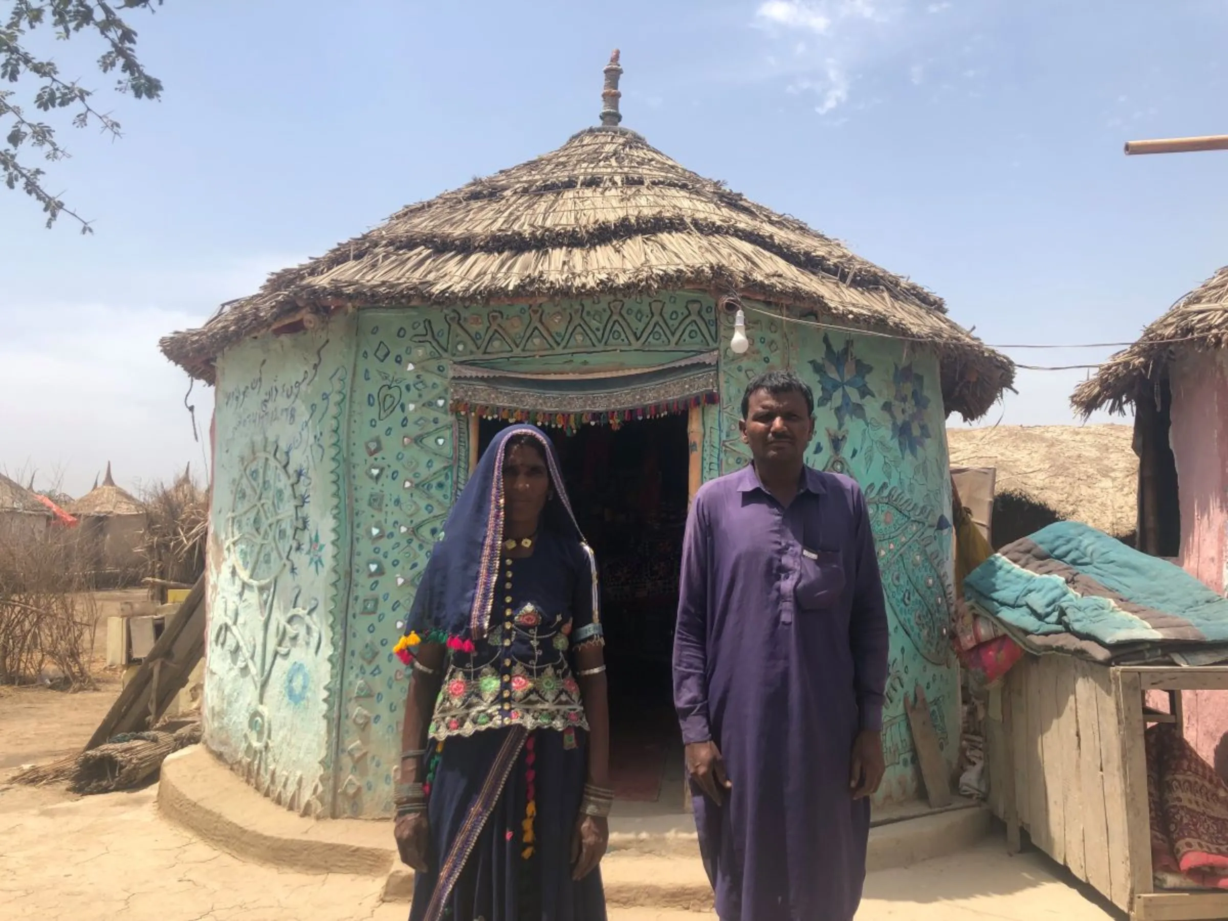 Dhani and her husband Khumo Umro pose outside their safe room in Pono village, Tando Allah Yar District, Pakistan, April 9, 2023. Thomson Reuters Foundation/Zofeen T. Ebrahim