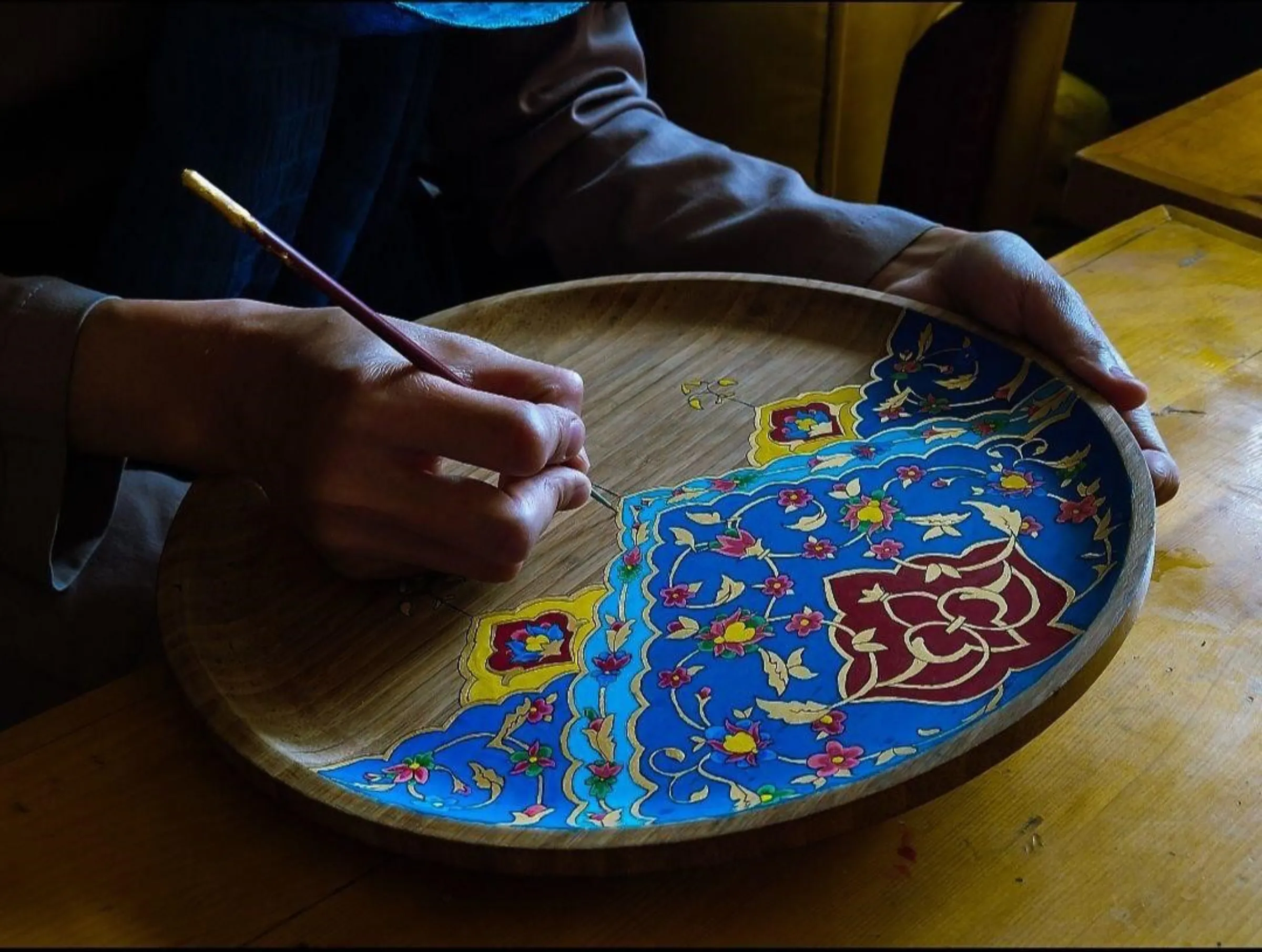 An Afghan woman paints a tray at a handicraft centre in Kabul run by Laila Haidari. Photo taken August 2023. Handout/Thomson Reuters Foundation