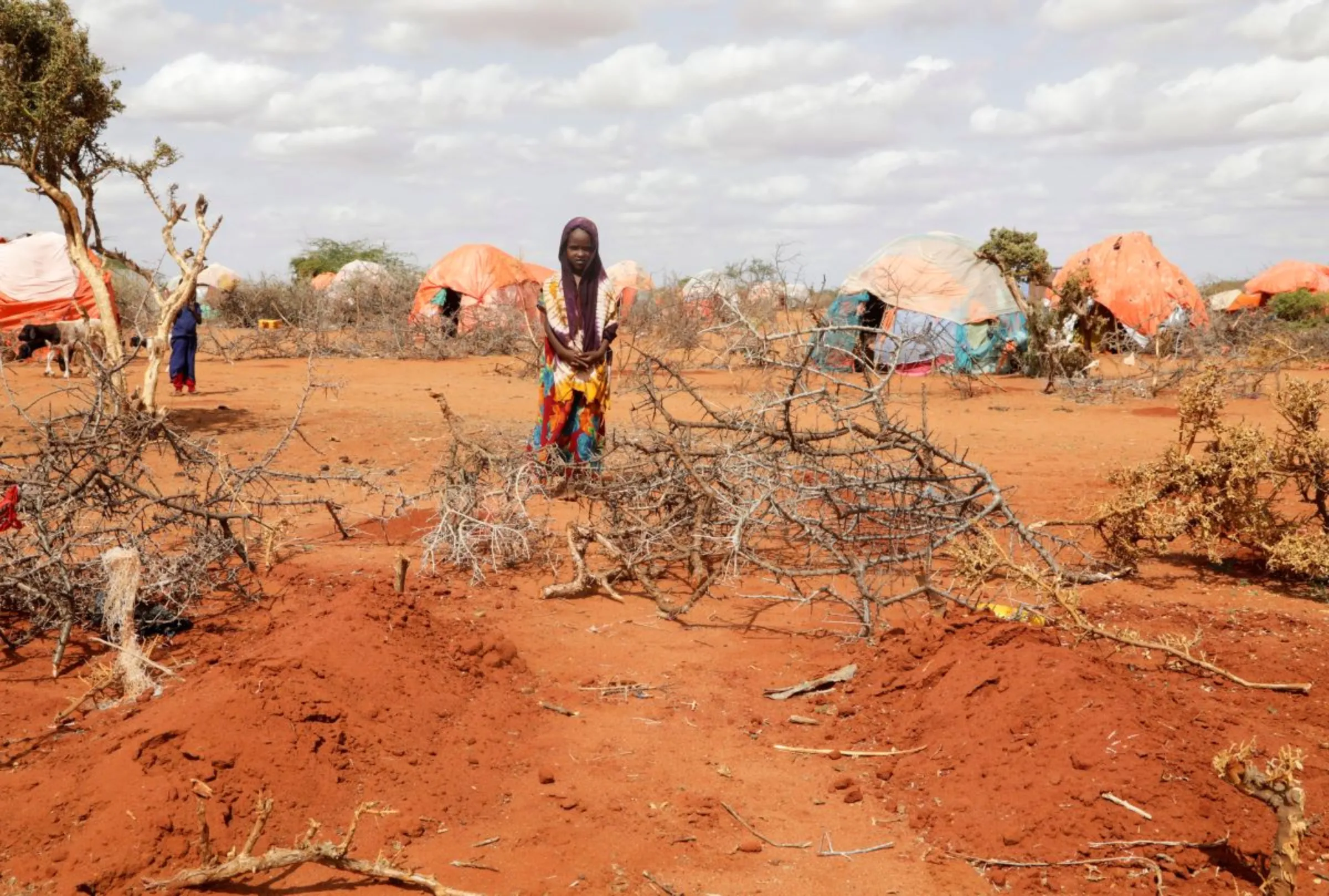 Kafia Noor, 5, stands near the grave of her twin sisters Ebla and Abdia who died of hunger at the Kaxareey camp for the internally displaced people in Dollow, Gedo region of Somalia May 24, 2022. REUTERS/Feisal Omar