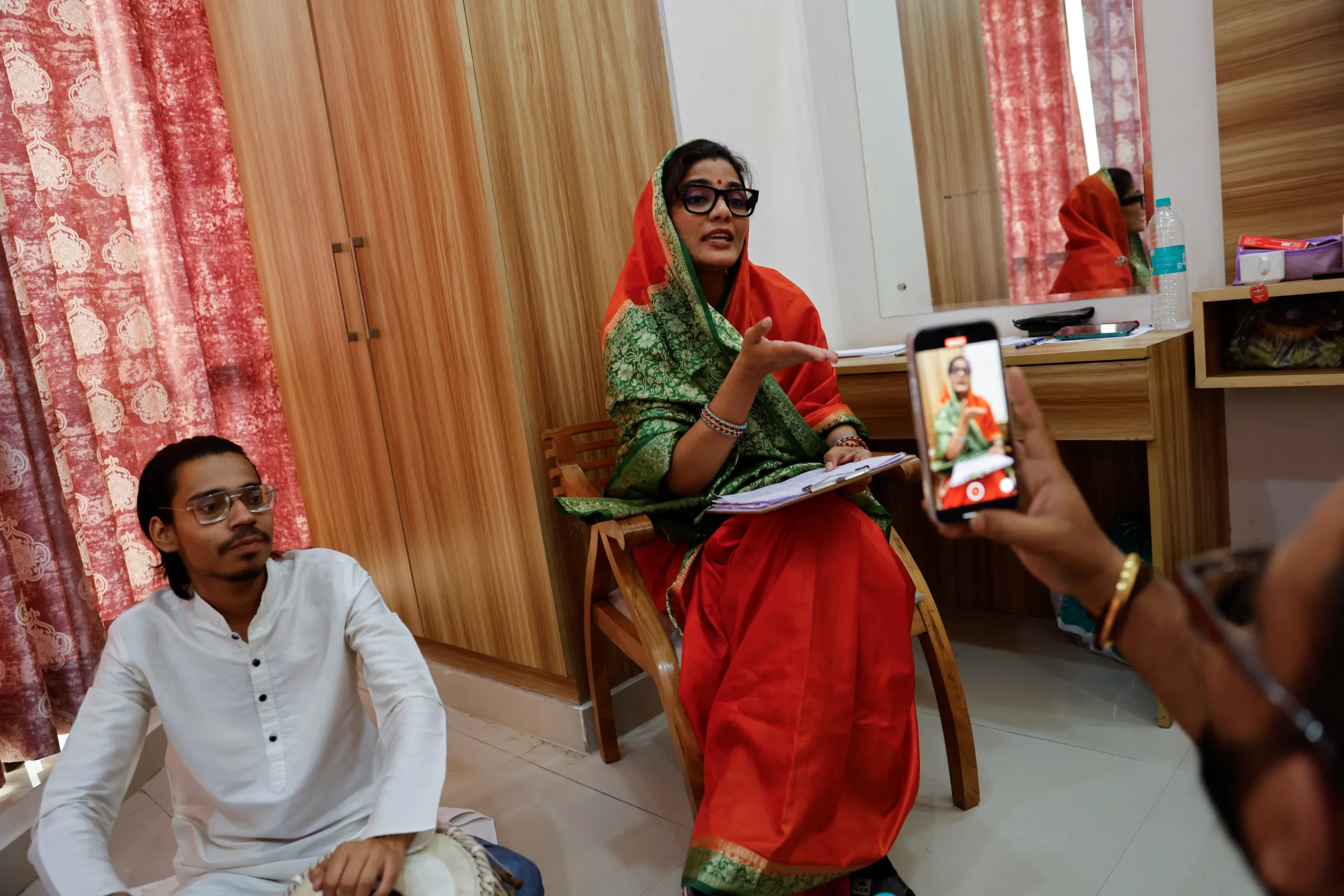 A social media content creator sings a song while her husband records the songs on a mobile phone at their room in a hotel in Noida, India, April 5, 2024. REUTERS/Anushree Fadnavis