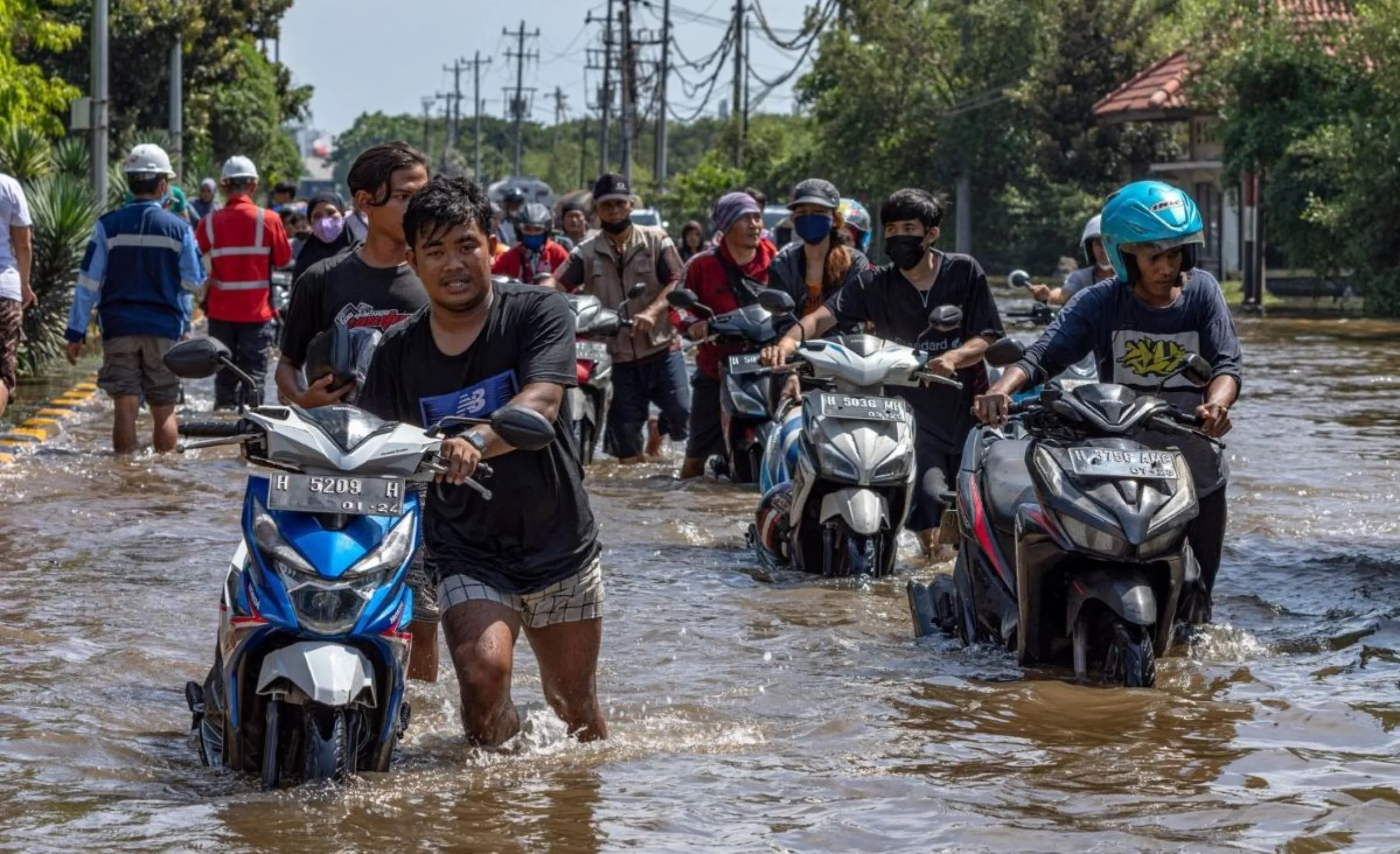 Workers push their motorbike through the water at Tanjung Emas container port terminal area which got flooded following high tides and broken seawalls, in Semarang, Central Java province, Indonesia, May 24, 2022