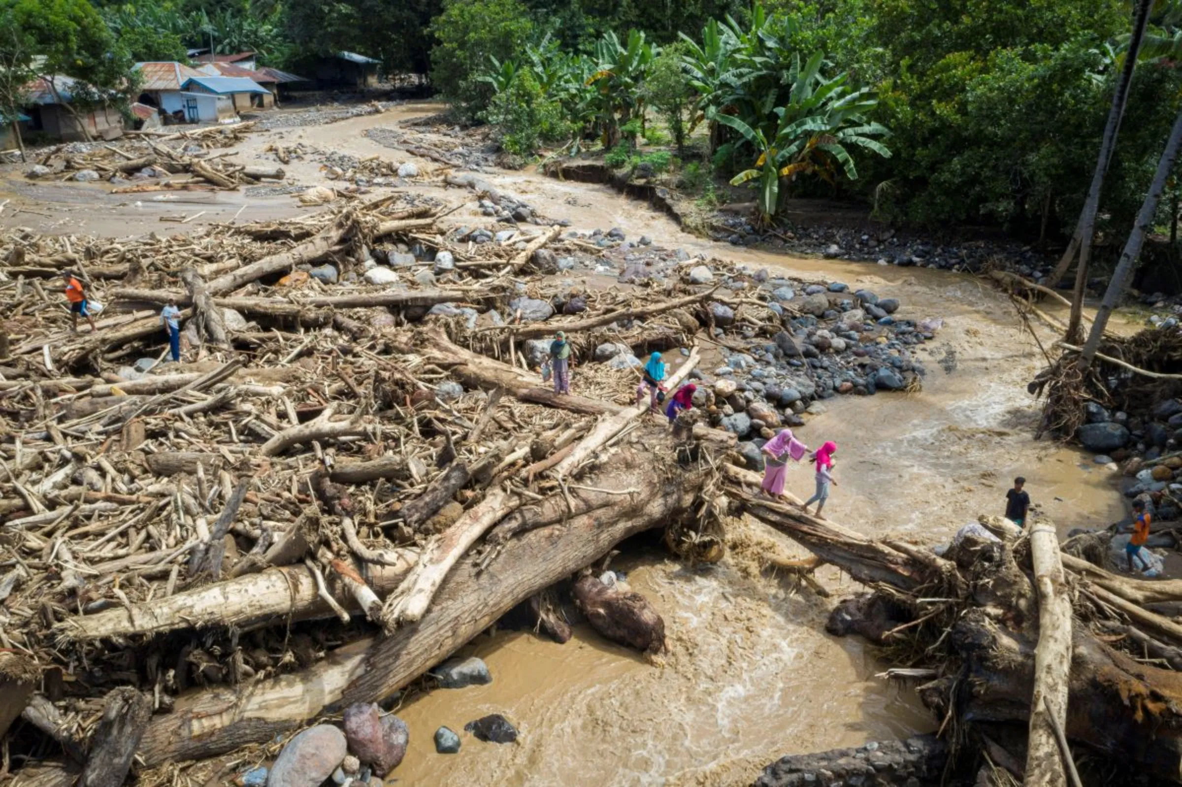 An aerial picture shows people walking through a pile of tree trunks after flash floods triggered by tropical cyclone Seroja in East Flores, East Nusa Tenggara province, Indonesia April 7, 2021