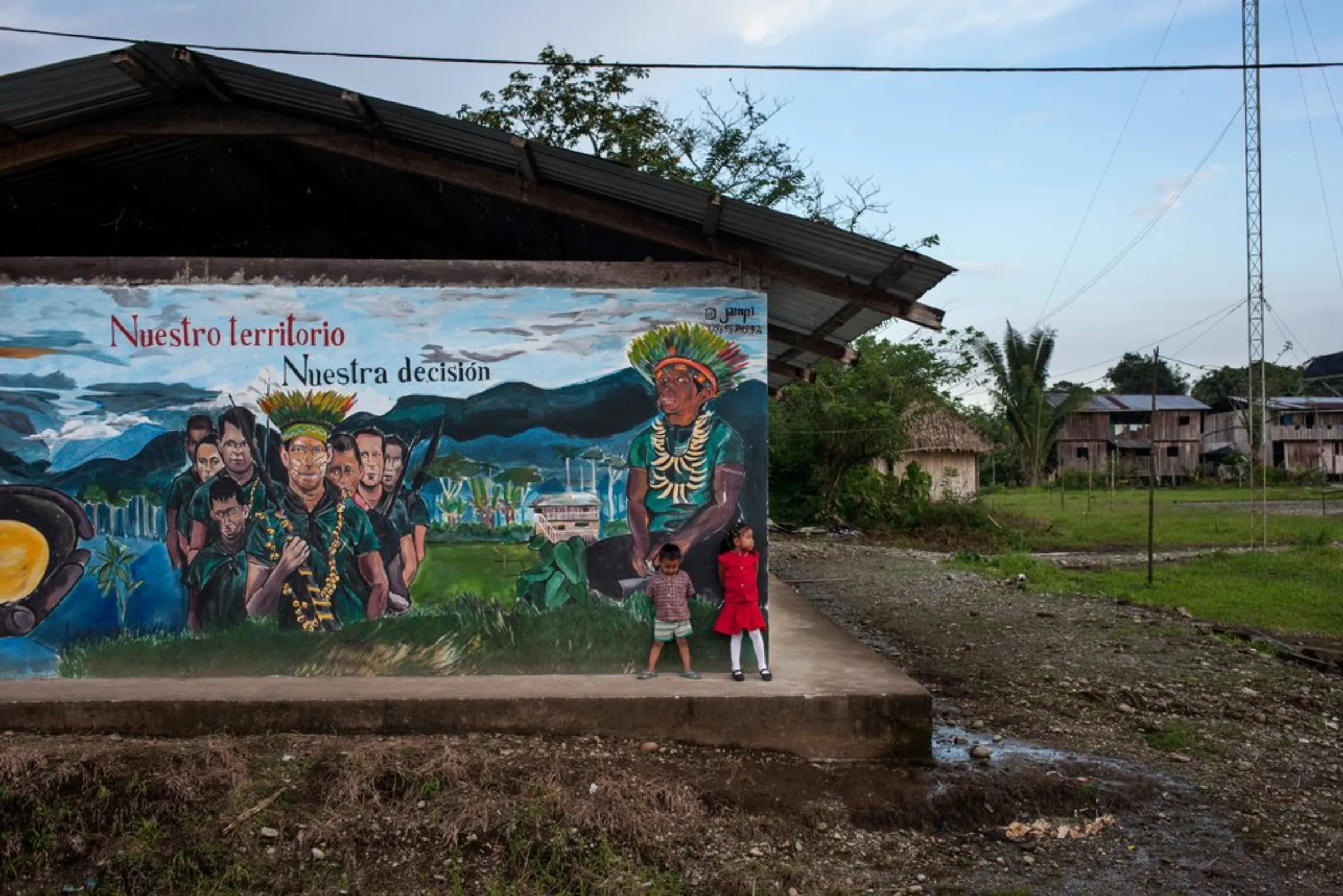 Children stand near a painted mural with the slogan, 'Our territory, our decision' at the Cofan village of Sinangoe in Ecuador’s northern rainforest, on April 21, 2022. In February, the Cofan celebrated a rare victory when Ecuador's constitutional court ratified a ruling that had suspended 52 formal gold mining concessions on their lands