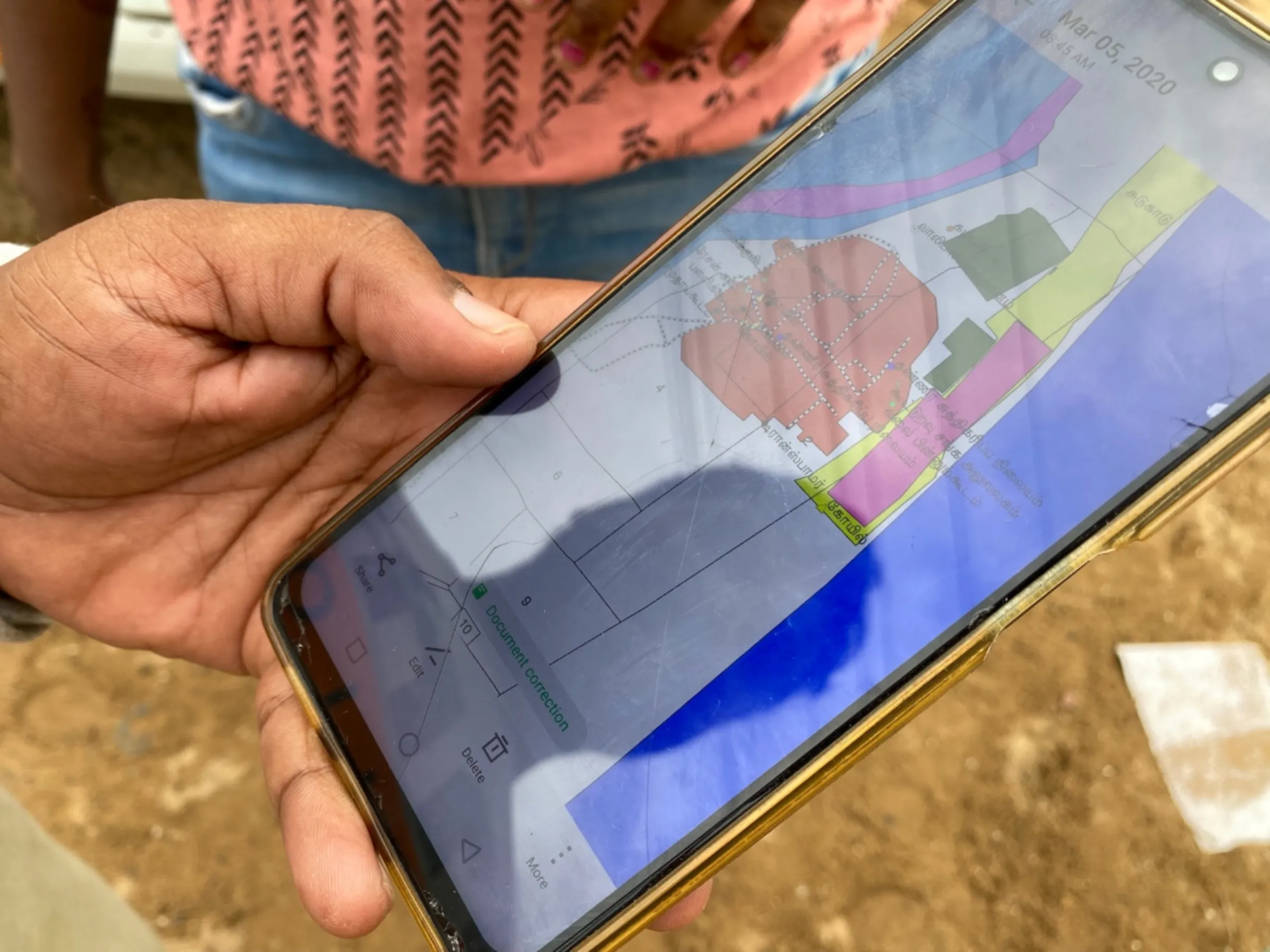 Bharath S Raji holds out his smartphone to show a map of Gunankuppam village through a fisherman’s eyes, in Gunankuppam, near Chennai, India, July 14, 2023