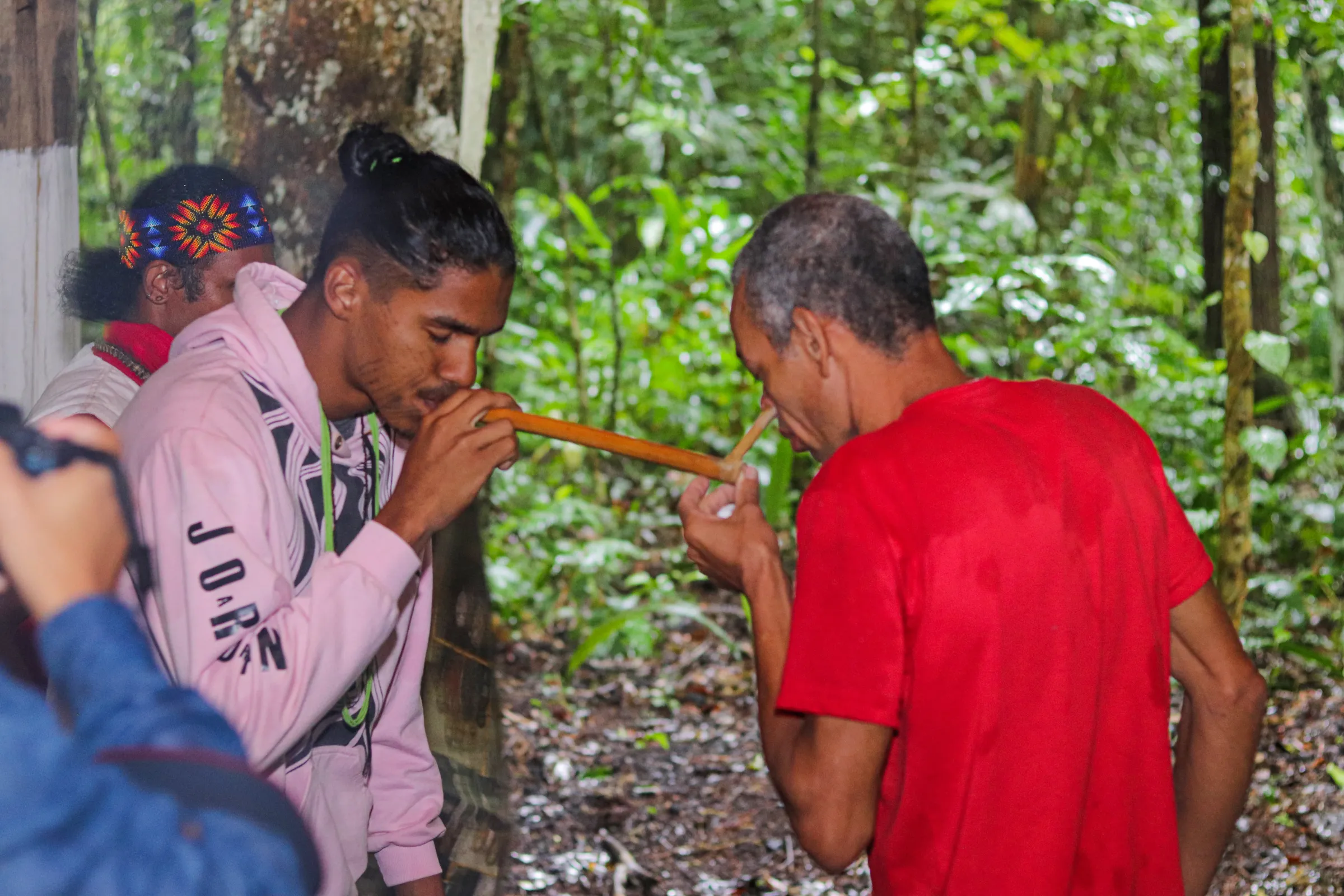 An Indigenous Pataxó blows ceremonial powder into the nostrils of Pataxó Erisvaldo Pereira near forest in the Aldeia Velha territory, near Arraial D'Ajuda in Porto Seguro district, Brazil, April 22, 2023. Thomson Reuters Foundation/Rogério Naba