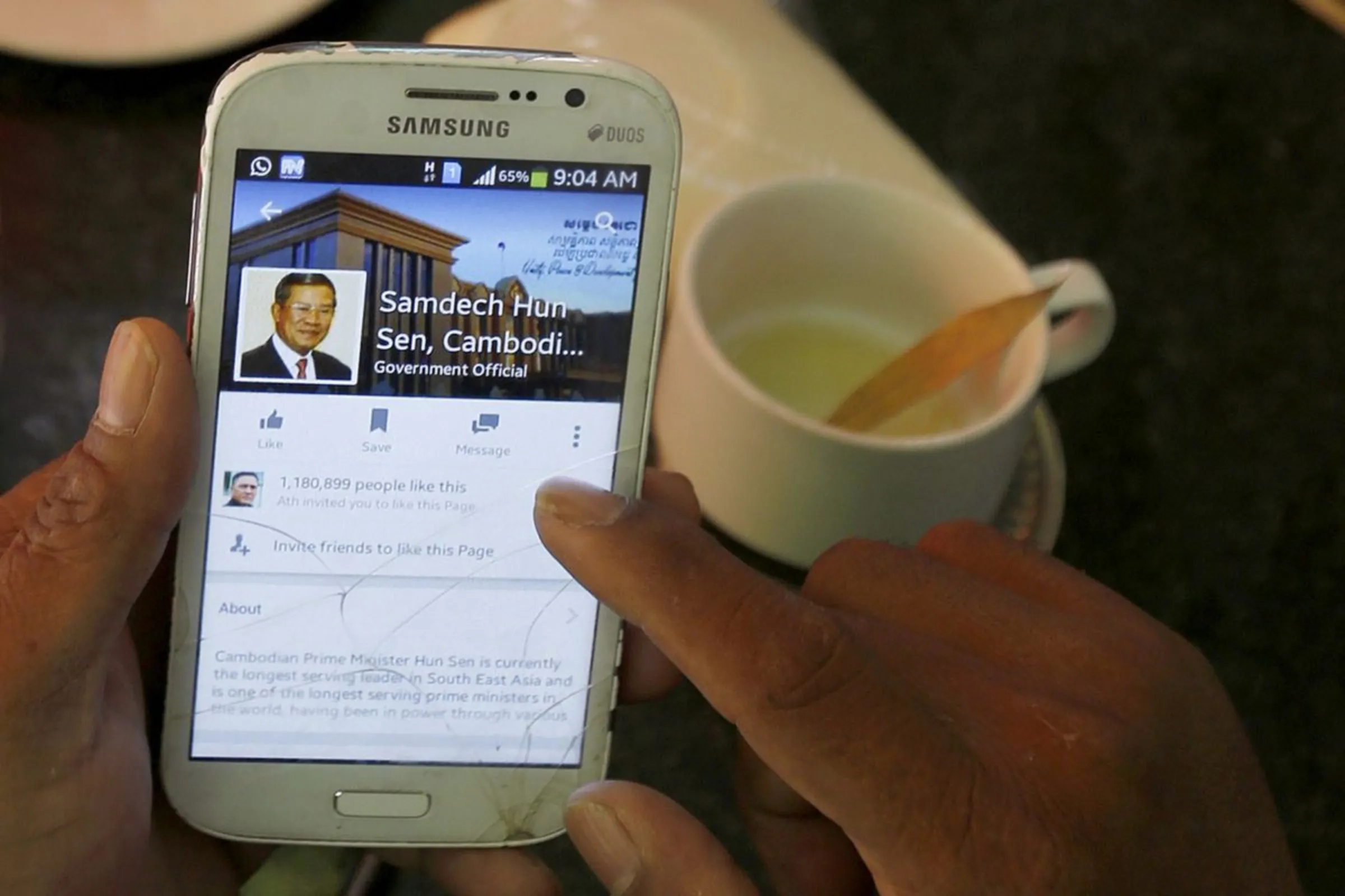 A person uses a smartphone to look at the Facebook page of Cambodia's Prime Minister Hun Sen, during breakfast at a restaurant in central Phnom Penh, Cambodia October 7, 2015