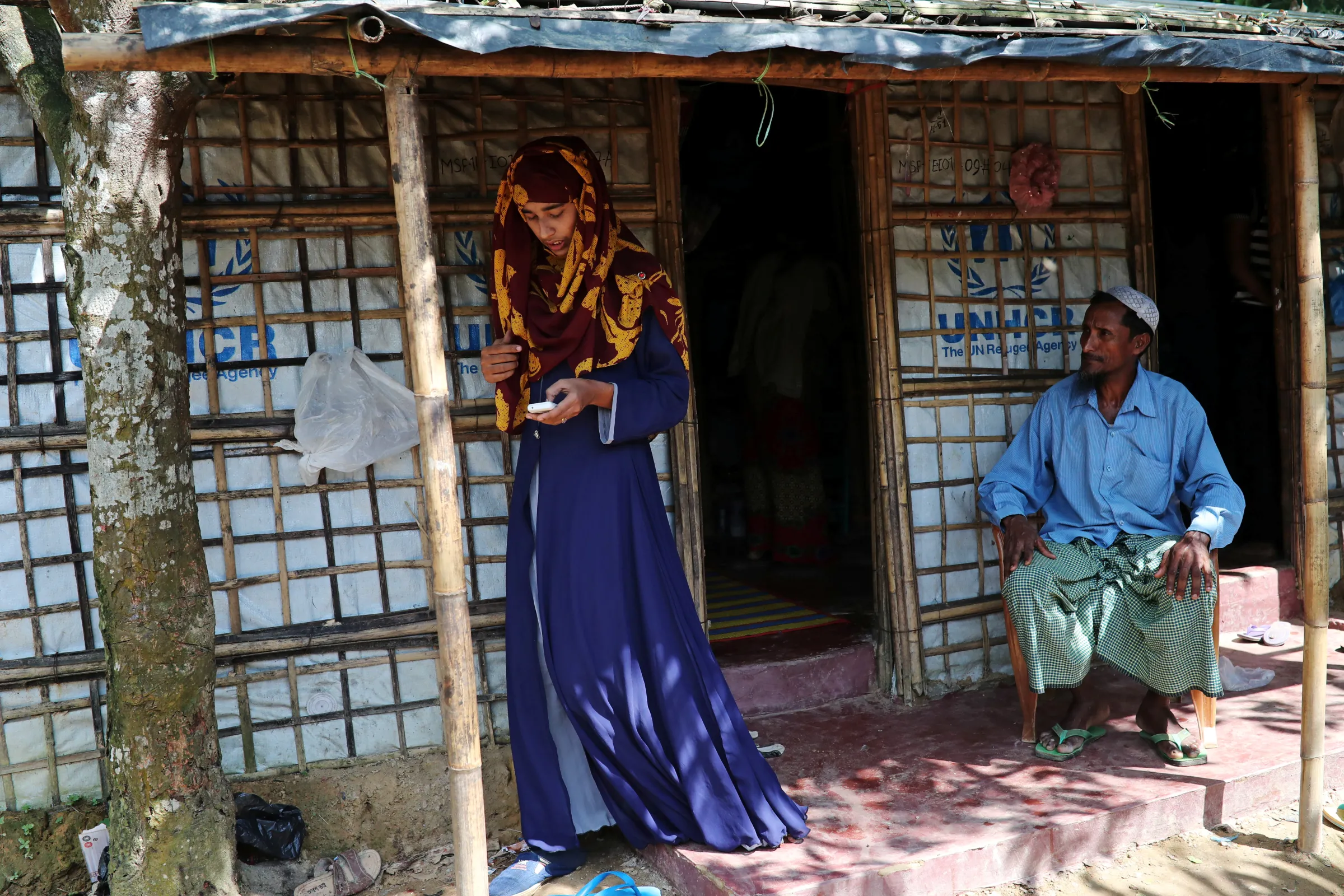 A Rohingya refugee girl, uses her mobile phone as her father Mohammad Hossain watches before she departs for Chittagong to attend school at the Asian University for Women, in Cox's Bazar, Bangladesh, August 24, 2018