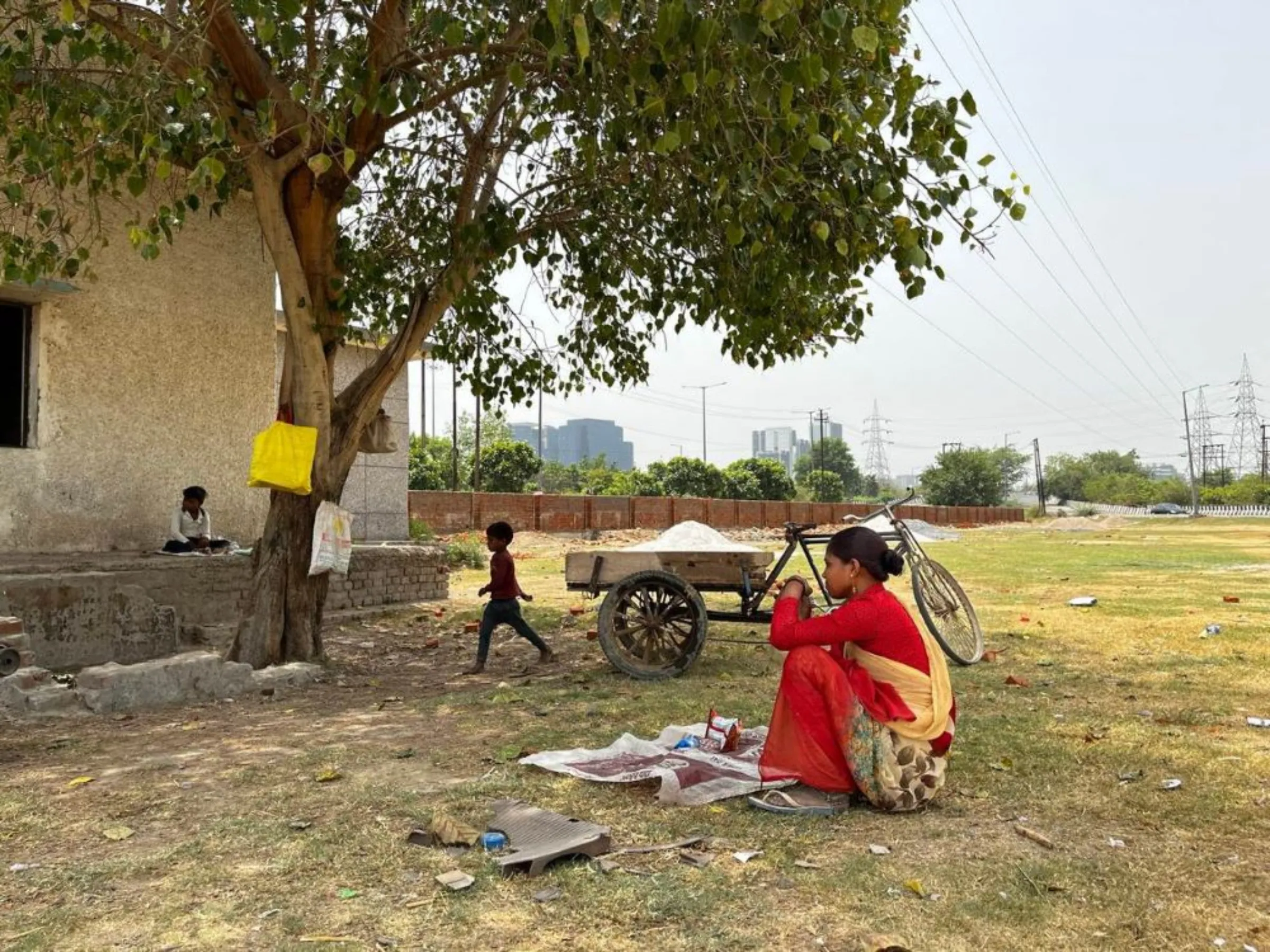 A woman labourer and her two children sit under a tree at a construction site during an intense heatwave in Noida, India, May 18, 2022