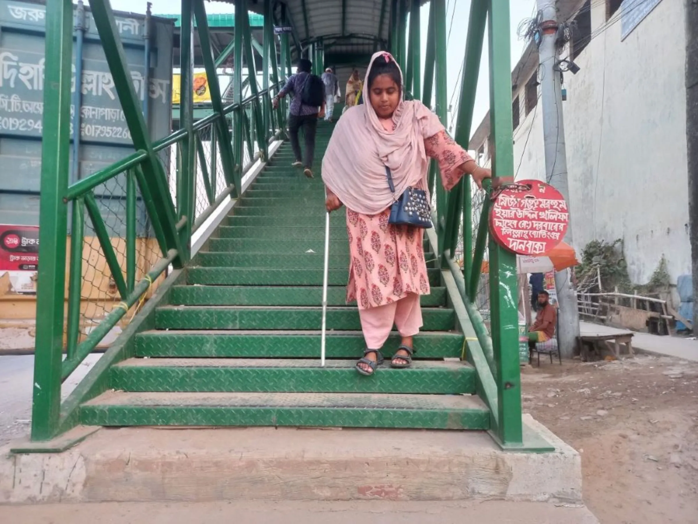 Yanoor Akter, one of the survivors of the 2013 Rana Plaza collapse, walks down stairs in Dhaka, Bangladesh, April 10, 2023. Akter is still looking for secure employment that will not discriminate against her disability