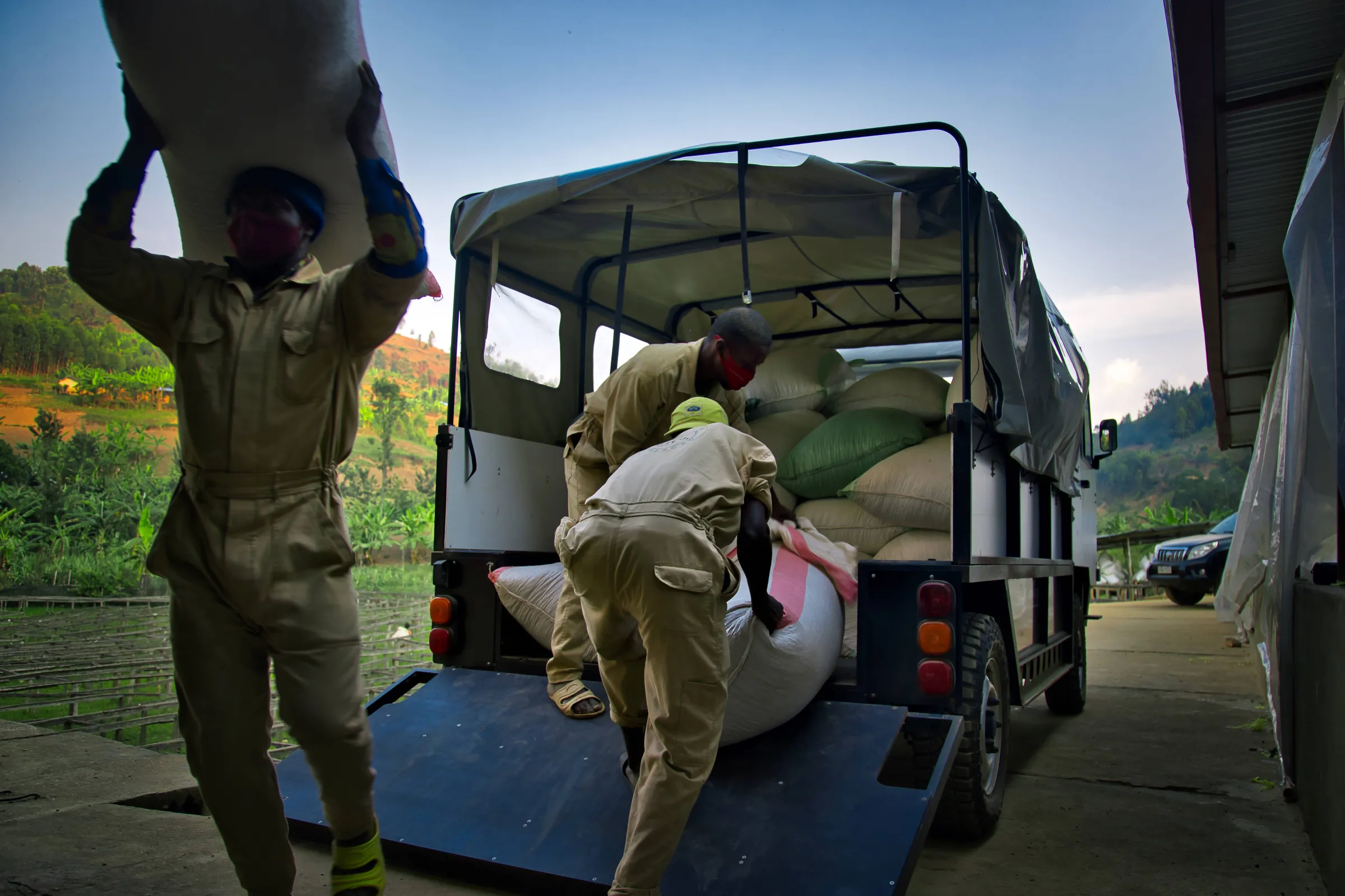 Men offload large bags of produce from an OX truck in Nyamasheke, Rwanda. September 14, 2021. Thomson Reuters Foundation/ Handout via OX.