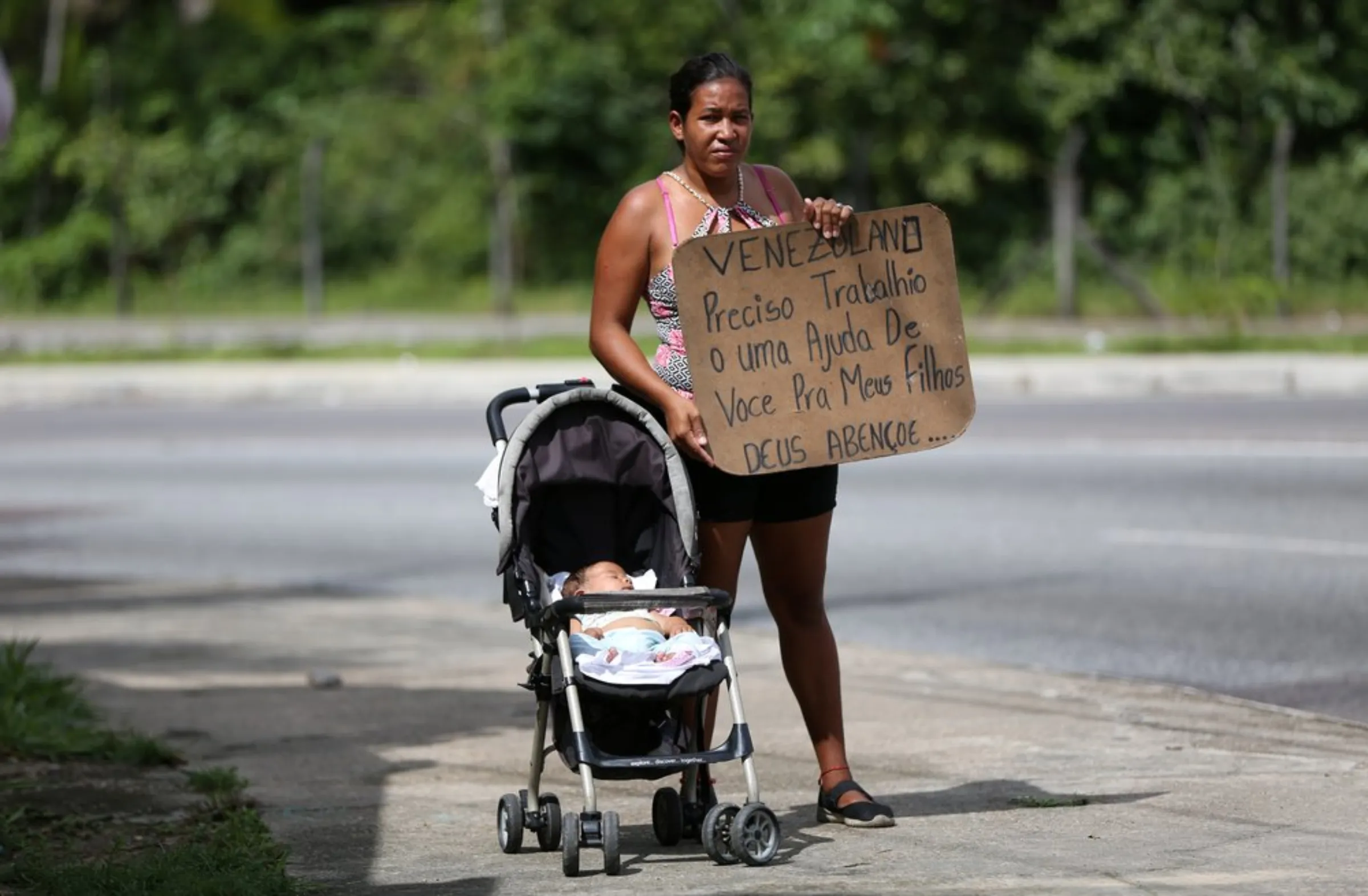 Venezuelan Liorkis Marke, 35, poses as she shows a cardboard that reads 'Venezuelan needs work or help for my children. God bless you' in Manaus, Brazil January 14, 2019