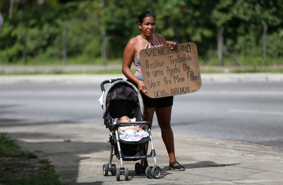 Venezuelan Liorkis Marke, 35, poses as she shows a cardboard that reads "Venezuelan needs work or help for my children. God bless you" in Manaus, Brazil January 14, 2019
